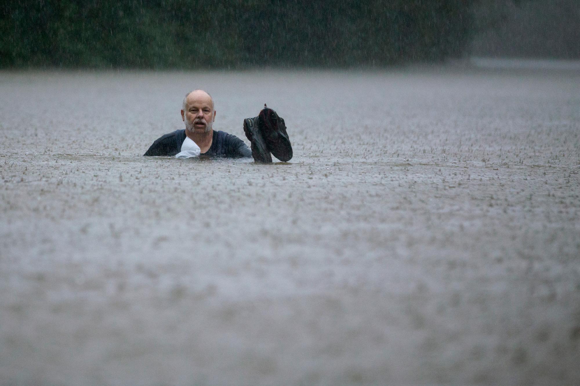 Un hombre vadea a través de las inundaciones causadas por las fuertes lluvias generadas por la depresión tropical Imelda inundó el área el jueves 19 de septiembre de 2019 en Patton Village, Texas. 