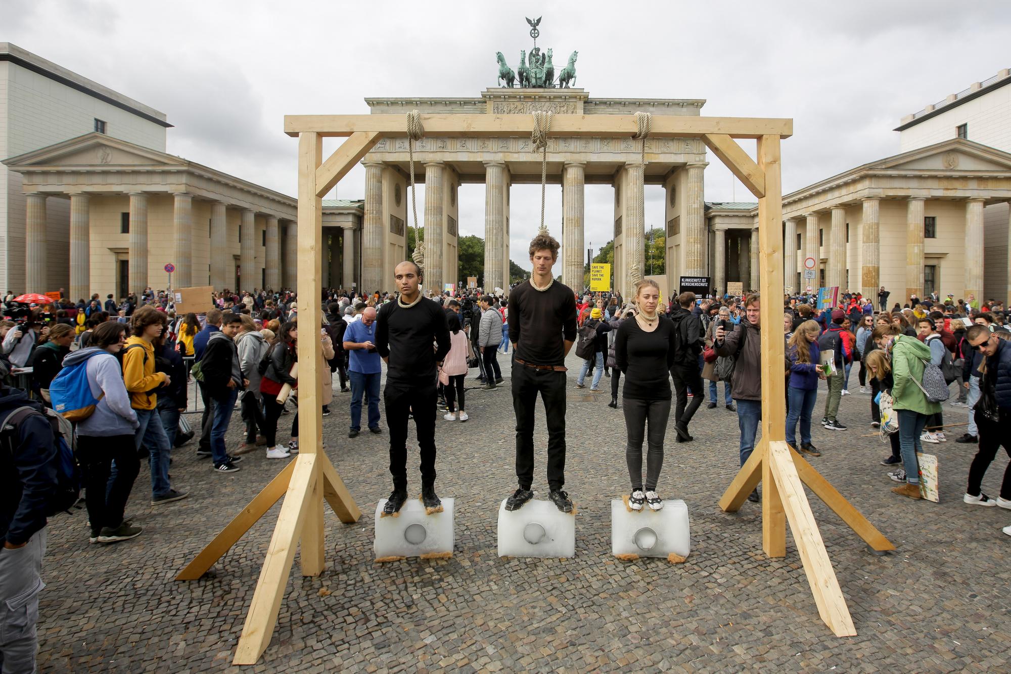 Tres personas se paran en bloques de hielo debajo de la horca para protestar contra la política climática antes de una protesta climática ‘Viernes para el futuro’ frente a la Puerta de Brandenburgo en Berlín, Alemania, el viernes 20 de septiembre de 2019. Protestas del ‘Viernes para el Futuro’ El movimiento contra el aumento de las emisiones de dióxido de carbono está previsto el viernes en ciudades de todo el mundo. En los Estados Unidos se planearon más de 800 eventos el viernes, mientras que en Alemania se esperan más de 400 manifestaciones. 
