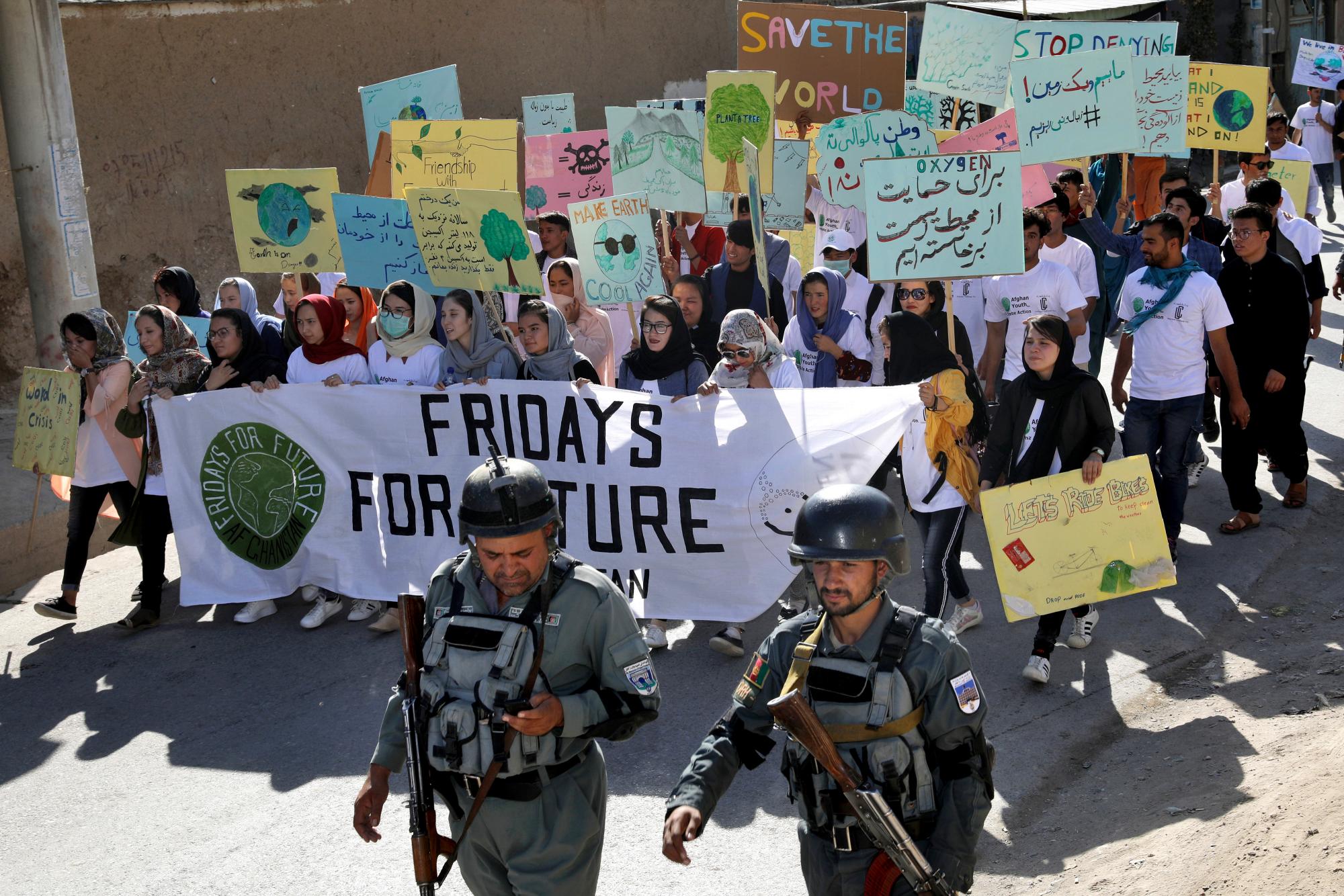 Los jóvenes asisten a un mitin de huelga climática, mientras las fuerzas de seguridad afganas los protegen en Kabul, Afganistán, el viernes 20 de septiembre de 2019. En la capital afgana, donde la gente muere todos los días en horribles ataques con bombas, una generación joven, preocupada de que si la guerra no los mata, el cambio climático sí.