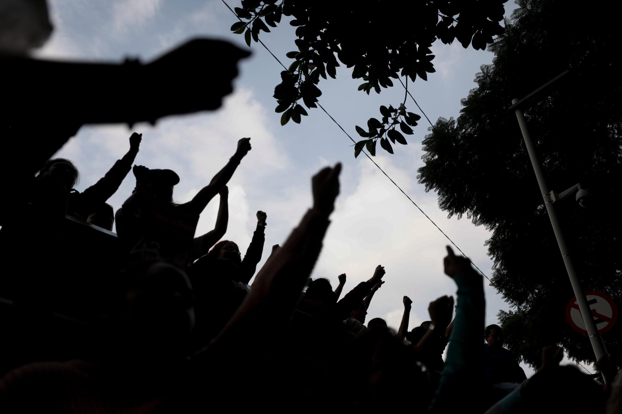 En esta imagen, tomada el 25 de septiembre de 2019, estudiantes levantan sus puños durante una protesta junto a los familiares de los 43 estudiantes de Ayotzinapa, en el exterior de la procuraduría general en la Ciudad de México. Las familias siguen reclamando justicia en el quinto aniversario de la desaparición de los jóvenes. 