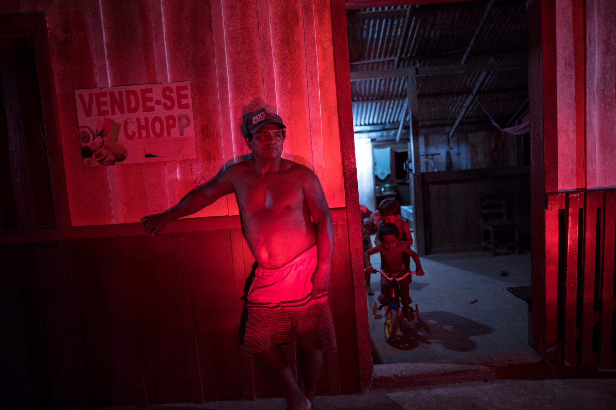 En esta imagen del 2 de septiembre de 2019, un tendero que vende objetos variados aparece iluminado por luces de freno ante su casa en el pueblo de Cajueiro, en el estado brasileño de Para. Los 900.000 indígenas de Brasil suponen en torno al 0,5% de la población, y sus reservas abarcan en torno al 14% del territorio. 