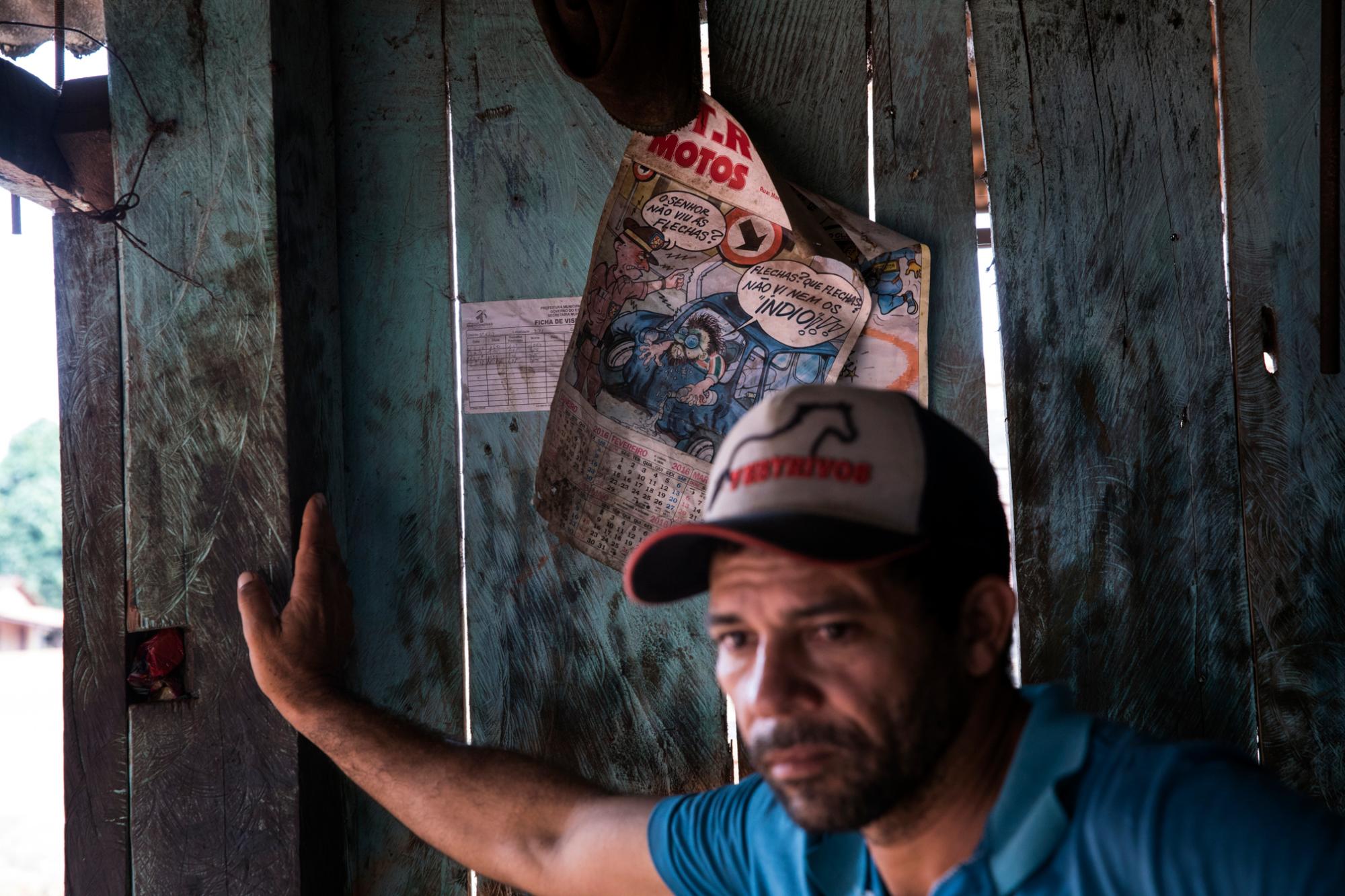 En esta imagen del 2 de septiembre de 2019, un cliente de pie junto a un calendario que muestra una caricatura burlándose de los indígenas en un taller mecánico junto a la carretera entre la ciudad de Paragominas y el poblado de Ka a kyr, en el estado brasileño de Para.