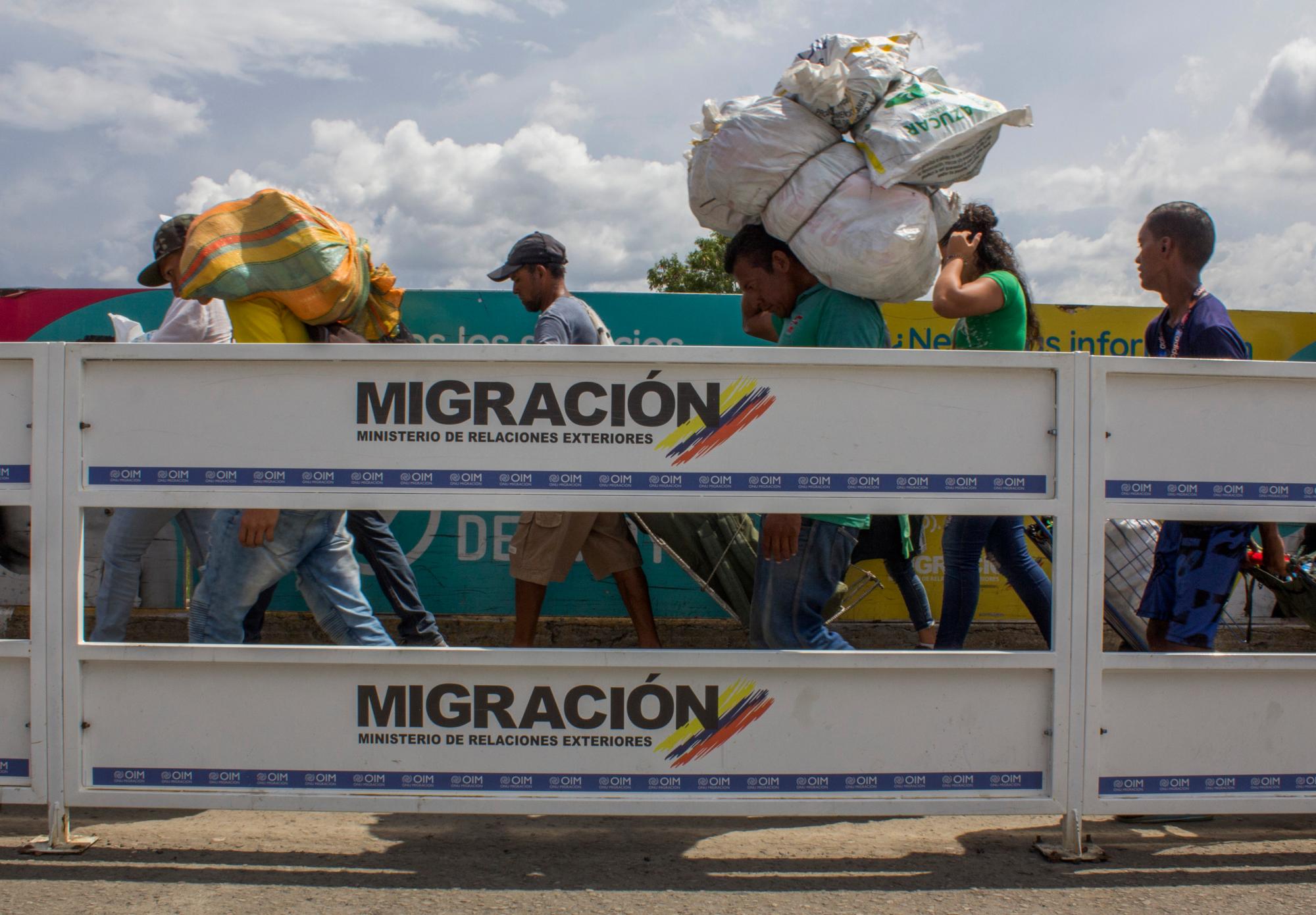 Hombres cargando grandes fardos a la espalda.