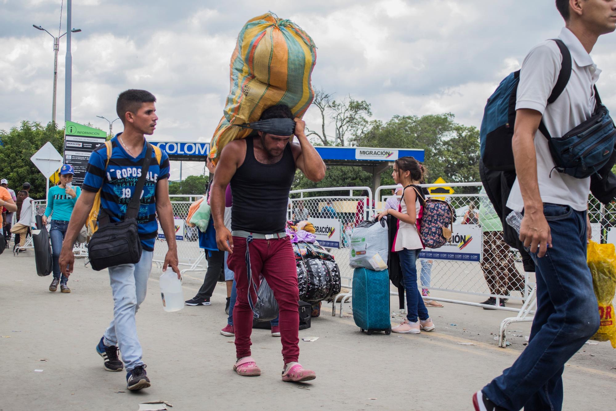 Un hombre carga un gran fardo a la espalda, con una cinta en la frente.