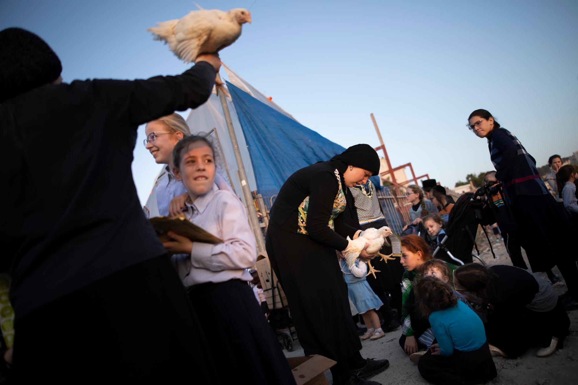 Ultra-Orthodox Jews swing chickens over their kids heads as part of the Kaparot ritual in Beit Shemesh, Israel, Sunday, Oct. 6, 2019. Observant Jews believe the ritual transfers ones sins from the past year into the chicken, and is performed before the Day of Atonement, Yom Kippur, the holiest day in the Jewish year which starts at sundown Tuesday. (AP Photo/Oded Balilty)