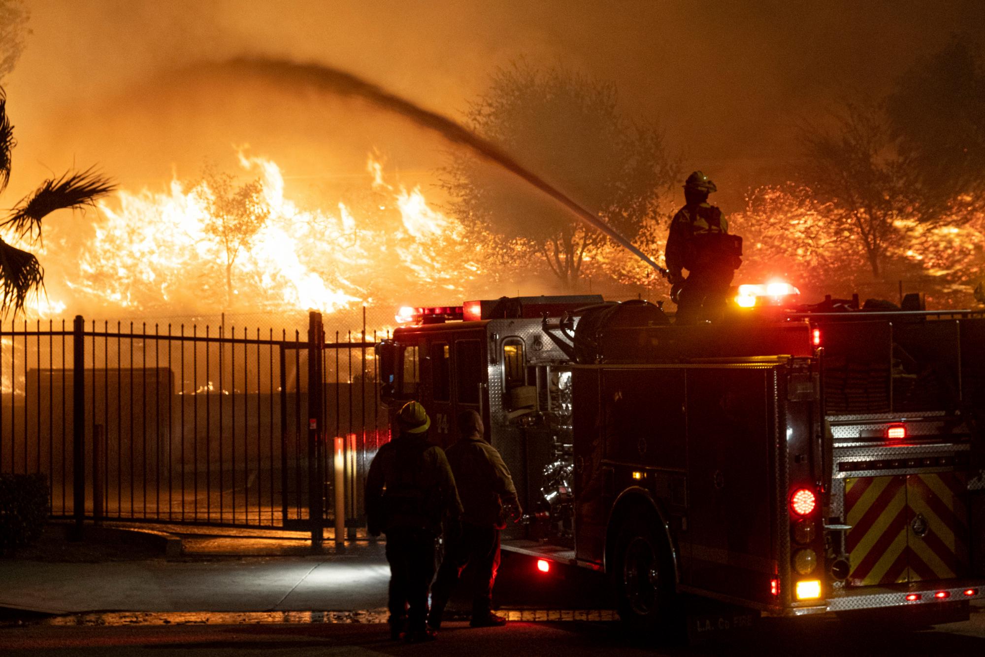 Los bomberos rocían agua sobre las llamas a lo largo de la calle Yarnell en Sylmar, California, el viernes 11 de octubre de 2019. El rápido viento impulsado por el viento se extendió rápidamente de Sylmar a Porter Ranch a última hora del jueves y temprano en la mañana del viernes, destruyendo varias casas. 