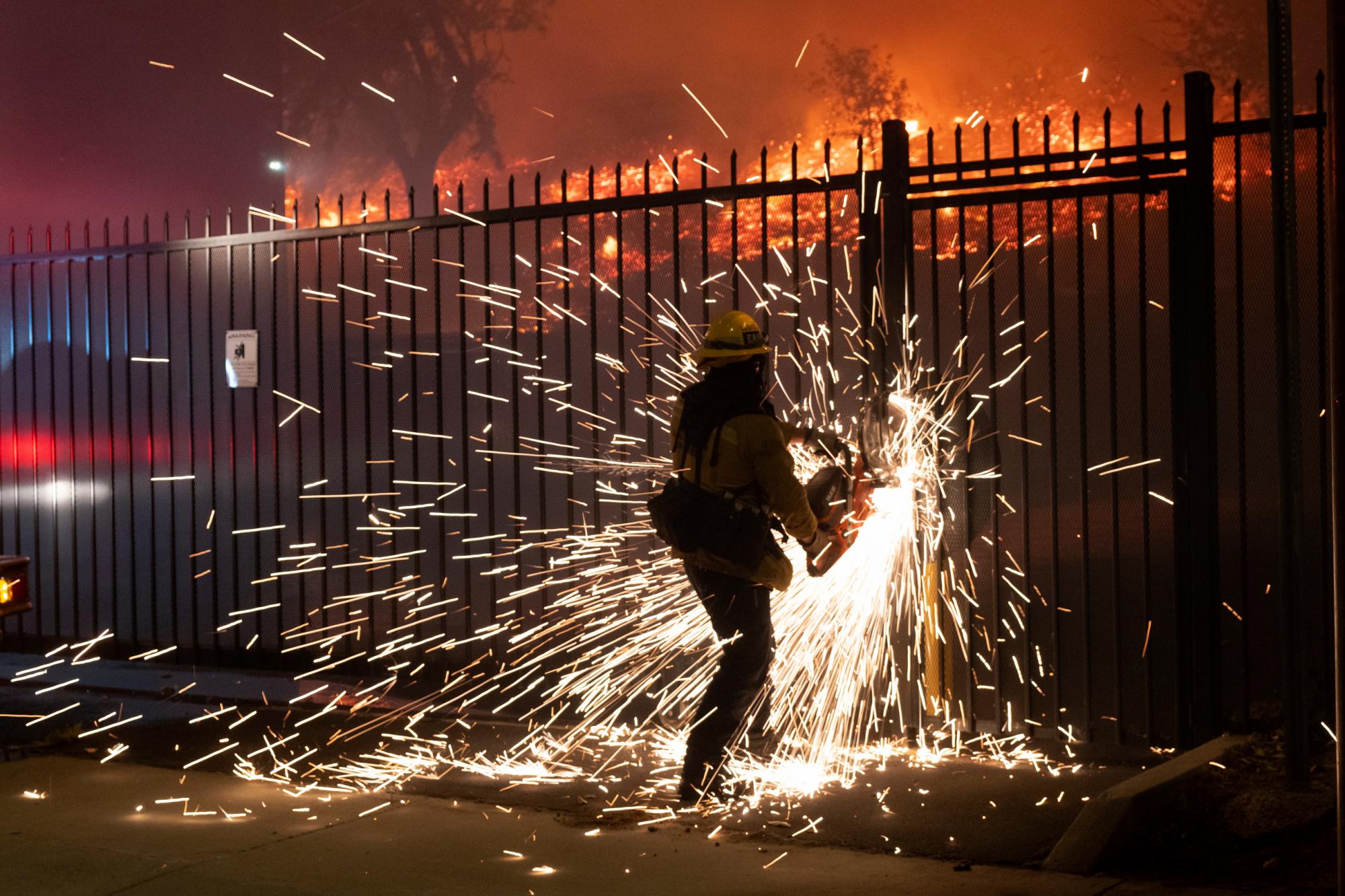 Un bombero corta una cerca para acceder al incendio de Saddleridge a lo largo de la calle Yarnell en Sylmar, California, el viernes 11 de octubre de 2019. 