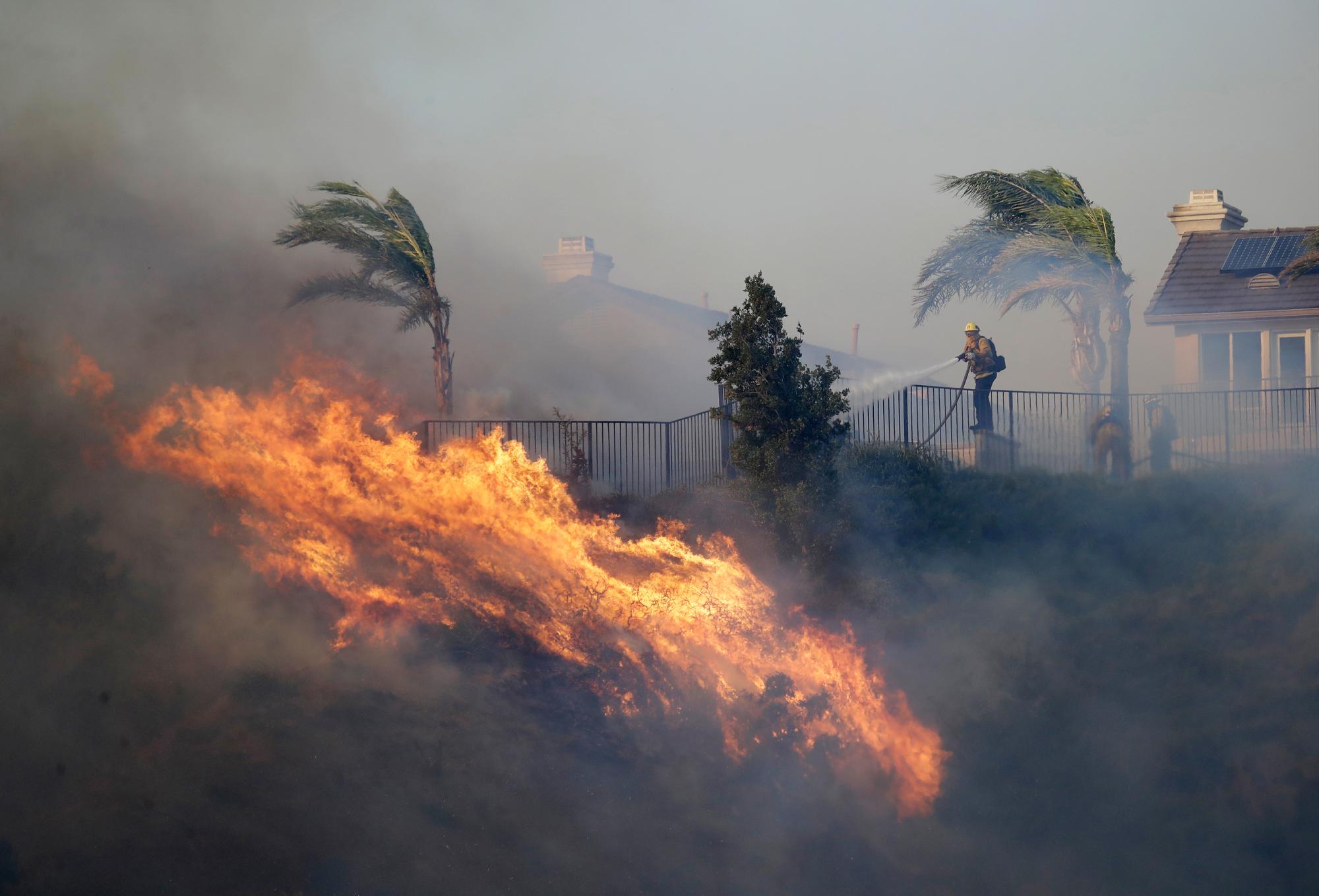 Un bombero rocía agua frente a un incendio forestal que avanza el viernes 11 de octubre de 2019 en Porter Ranch, California 