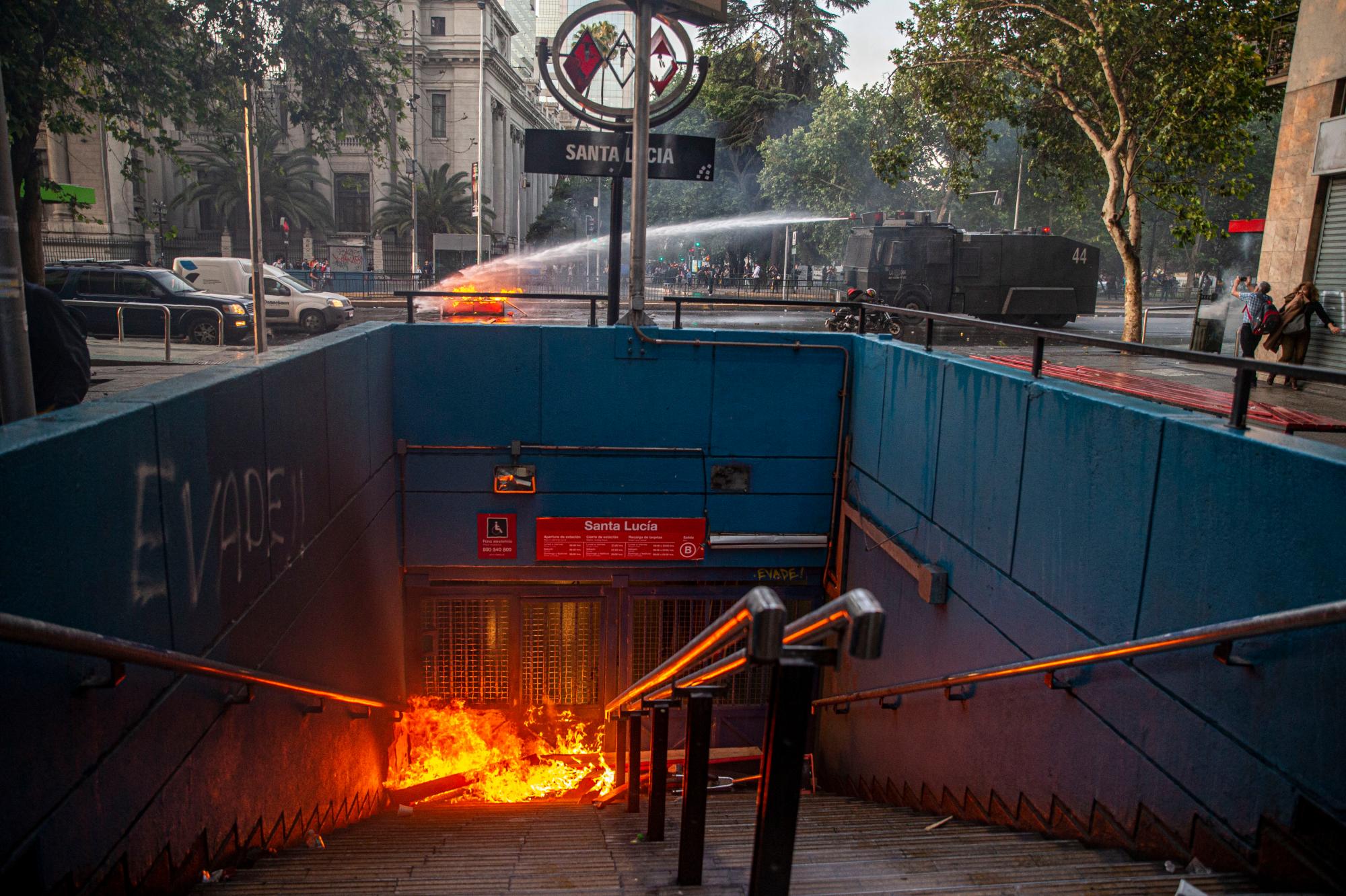Un cañón de agua de la policía apaga una barricada cerca de la estación de metro de Santa Lucía durante una protesta contra el aumento del costo de las tarifas de metro y autobús, en Santiago, el viernes 18 de octubre de 2019. 