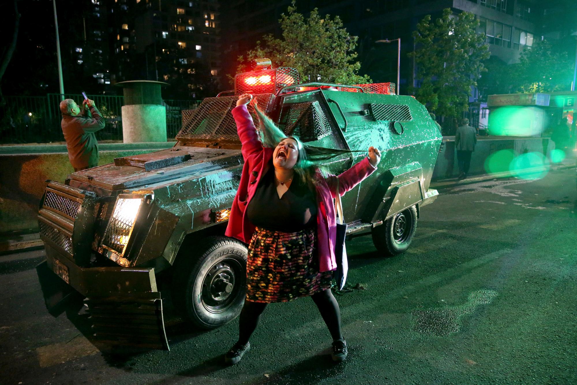 Una mujer grita frente a un camión de policía cerca de la estación de metro de Santa Lucía durante una protesta contra el aumento del costo de las tarifas de metro y autobús, en Santiago, el viernes 18 de octubre de 2019. 