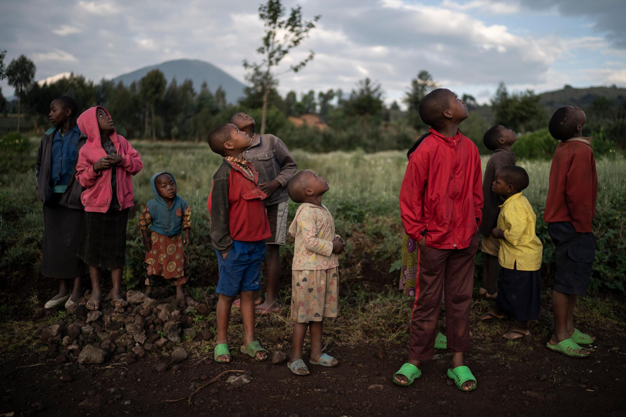 En esta foto del 7 de septiembre de 2019, los niños miran un avión no tripulado volando cerca del Parque Nacional de los Volcanes en Kinigi, Ruanda. En 2005, el gobierno adoptó un modelo para dirigir el 5% de los ingresos del turismo del Parque Nacional de los Volcanes para construir infraestructura en las aldeas circundantes, incluidas las escuelas y las clínicas de salud. Hace dos años, la participación se elevó al 10%. 
