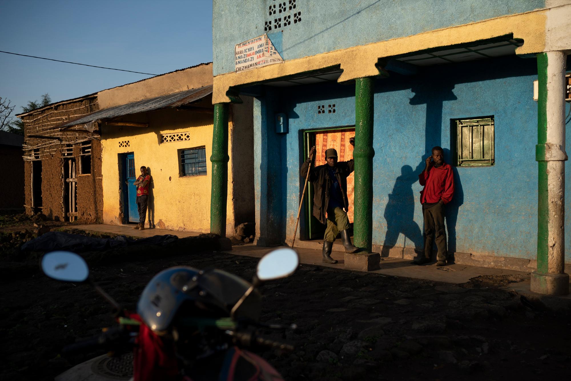 En esta foto del 4 de septiembre de 2019, los residentes se paran afuera de los edificios cuando sale el sol en Kinigi, Ruanda. En 2005, el gobierno adoptó un modelo para dirigir el 5% de los ingresos del turismo del Parque Nacional de los Volcanes para construir infraestructura en las aldeas circundantes, incluidas las escuelas y las clínicas de salud. Hace dos años, la participación se elevó al 10%. 