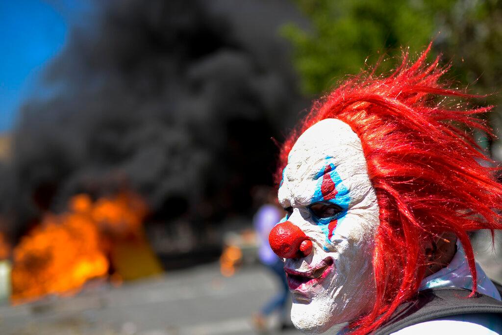 Un manifestante antigubernamental con una máscara de payaso participa en enfrentamientos con la policía en Valparaíso, Chile, el jueves 24 de octubre de 2019. El presidente Sebastián Piñera hizo más concesiones económicas el jueves y anunció un congelamiento en un aumento del 9.2% en los precios de la electricidad hasta el a fines del próximo año, para tratar de frenar una semana de protestas mortales por aumentos de precios y otras quejas 
