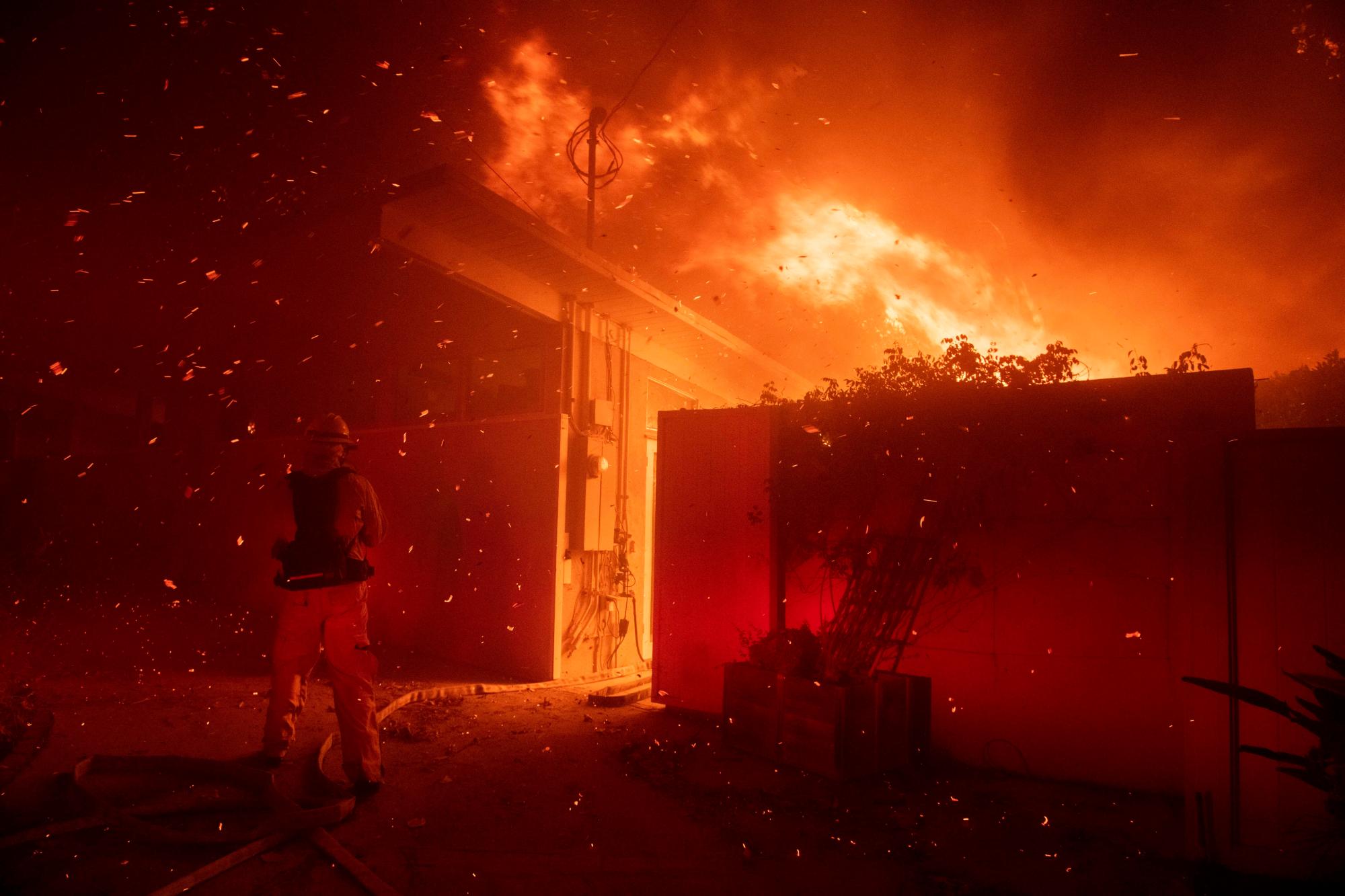 Los bomberos intentan salvar una casa de un incendio forestal en Tigertail Road el lunes 28 de octubre de 2019 en Los Ángeles, California 