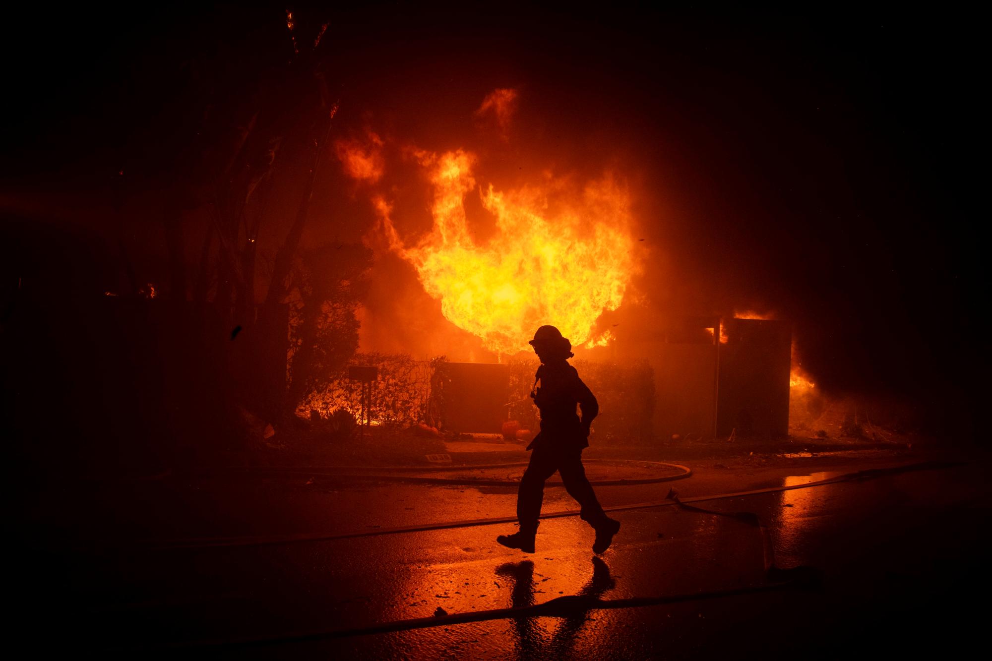 Los bomberos intentan salvar una casa en Tigertail Road durante el incendio de Getty, el lunes 28 de octubre de 2019, en Los Ángeles, California 