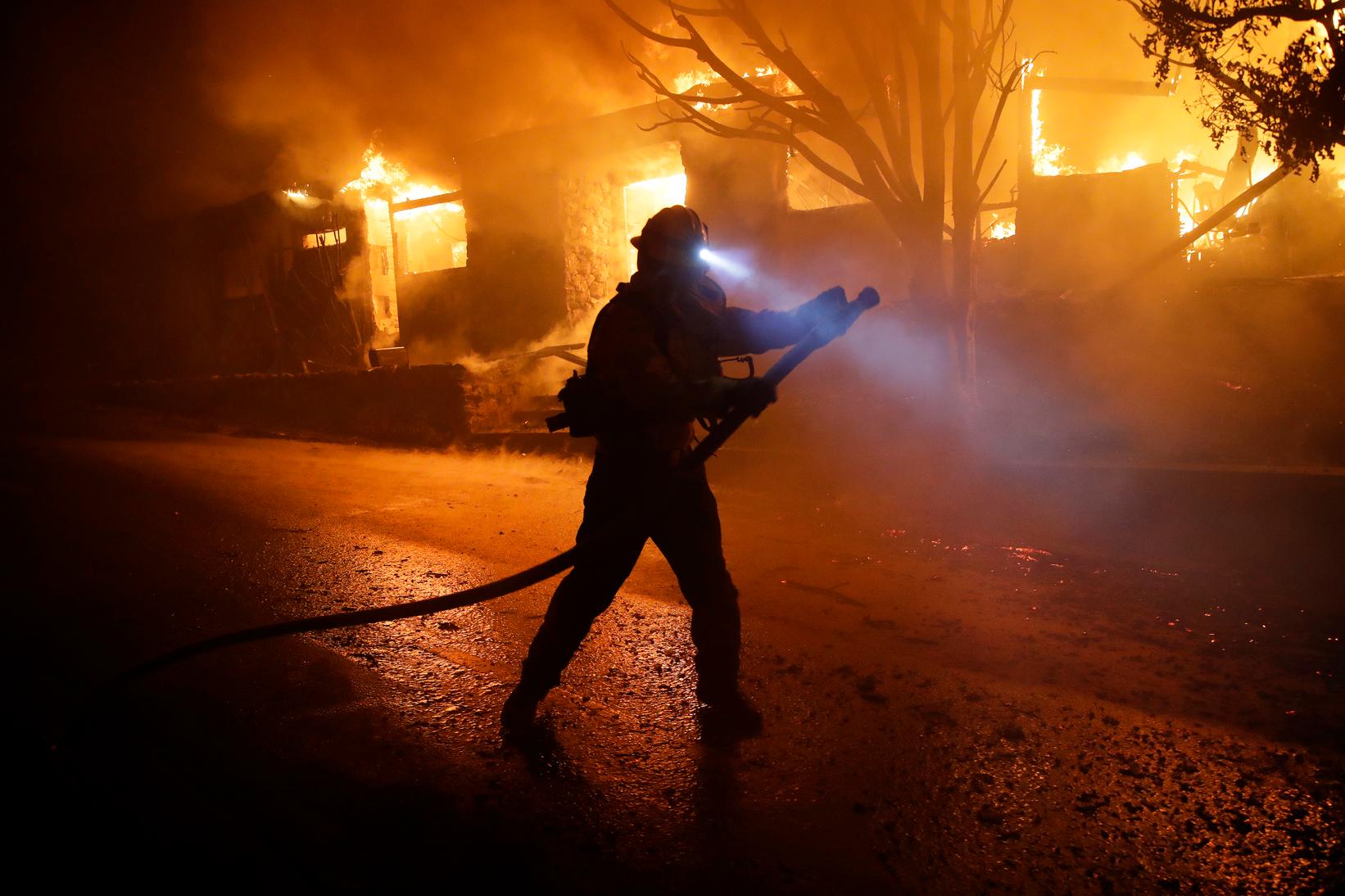 Un bombero se pone en posición para apagar las llamas mientras una casa arde en el área de incendios de Getty a lo largo de Tigertail Road el lunes 28 de octubre de 2019 en Los Ángeles. 
