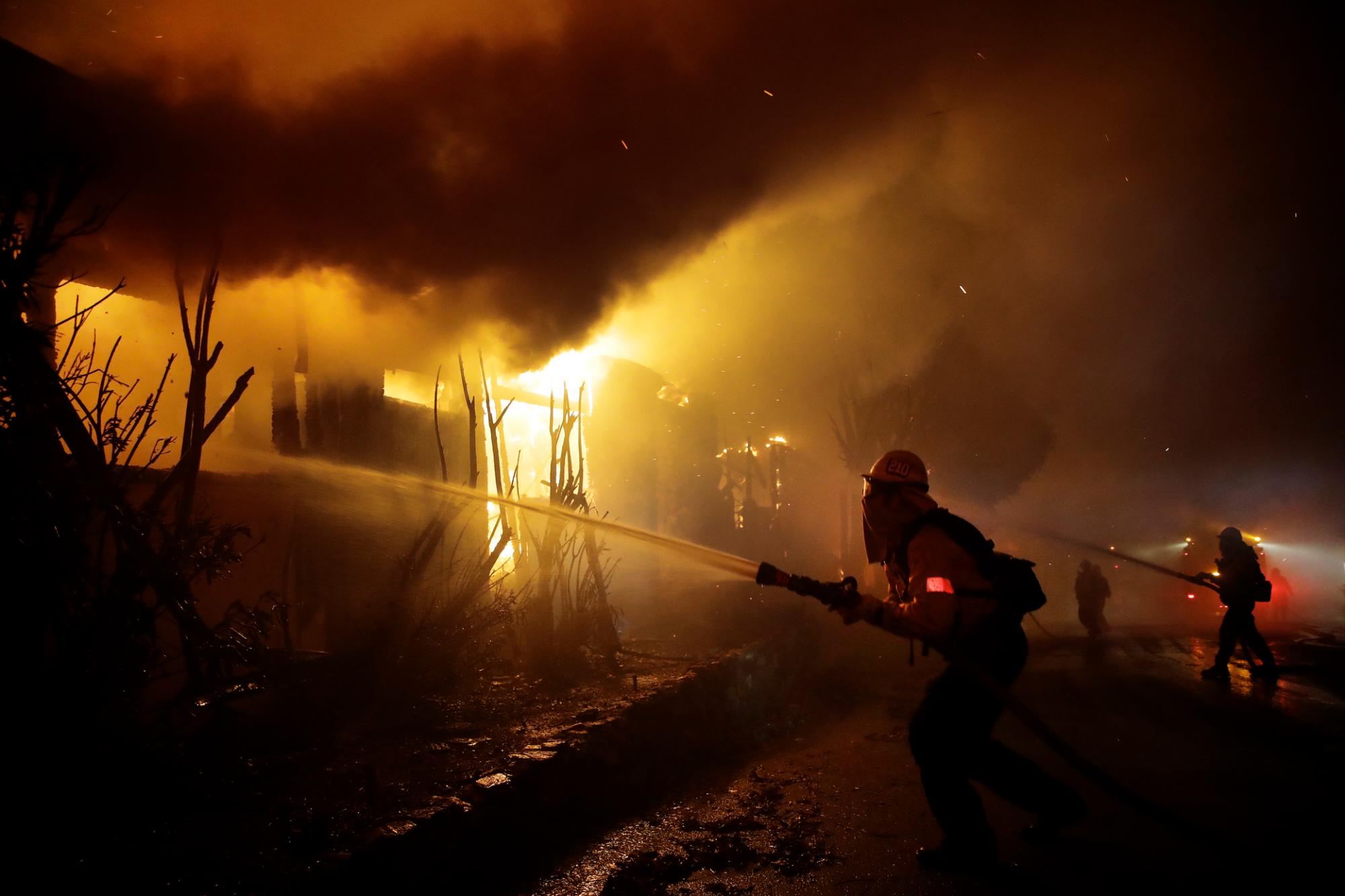 Firefighters try to hose down flames as homes burn in the Getty fire area along Tigertail Road, Monday, Oct. 28, 2019, in Los Angeles.