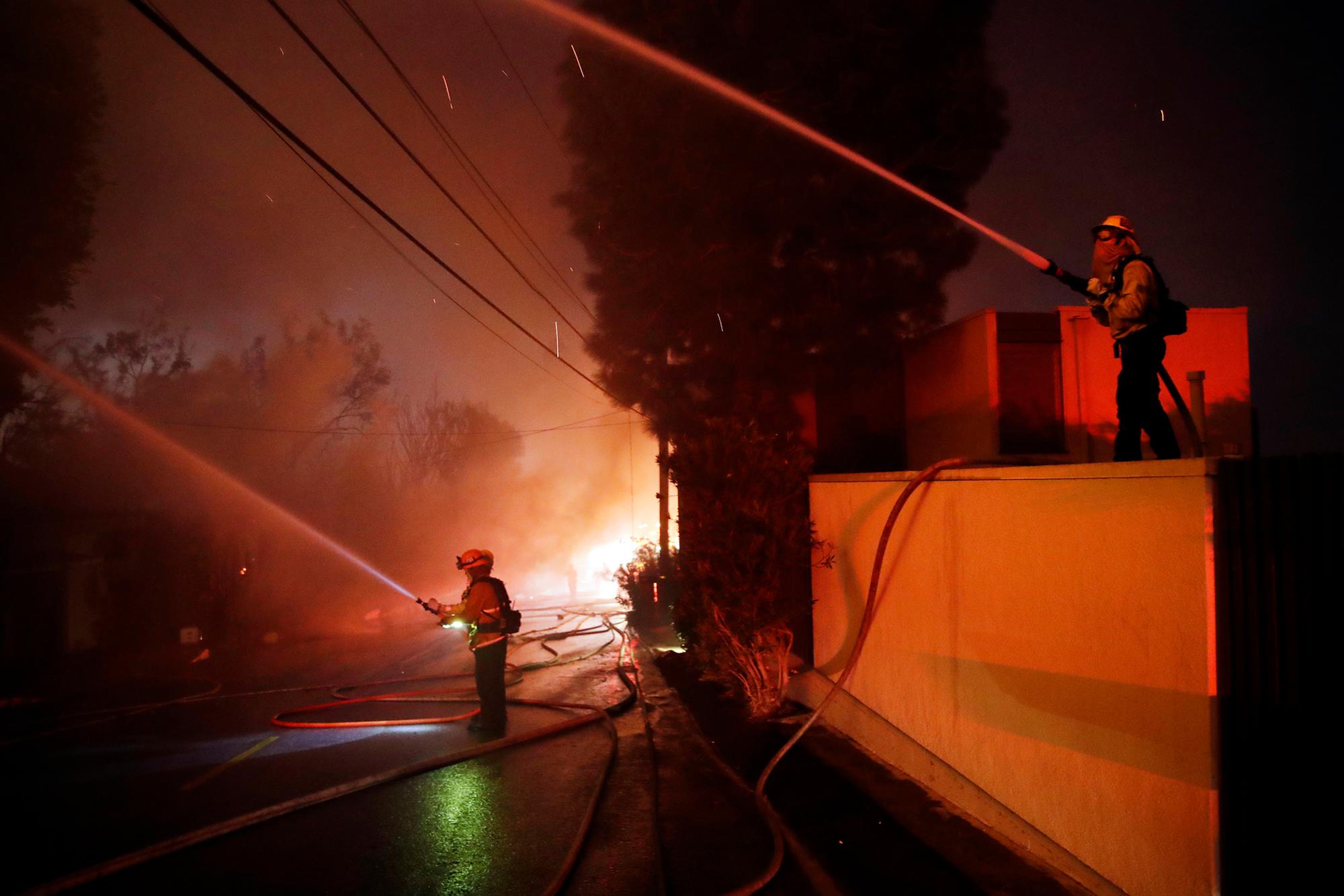 Los bomberos combinan esfuerzos mientras el incendio de Getty quema casas a lo largo de Tigertail Road, el lunes 28 de octubre de 2019 en Los Ángeles. 