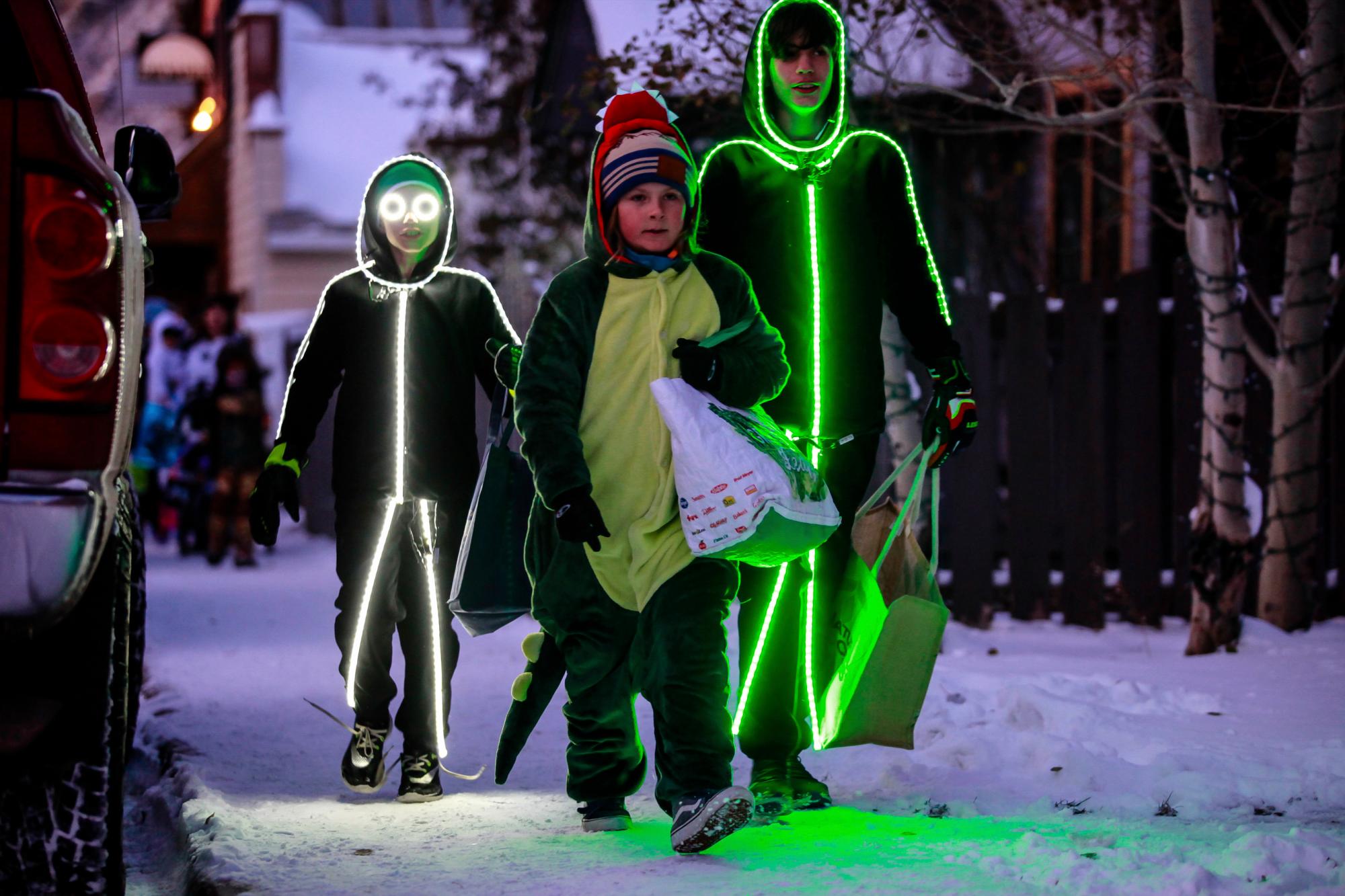 Los niños se iluminaron caminando por la calle durante el truco o trato anual de Minturn, Colorado, el miércoles 30 de octubre de 2019 en Minturn, Colorado. Los disfraces cálidos estaban de moda en el evento de este año. 