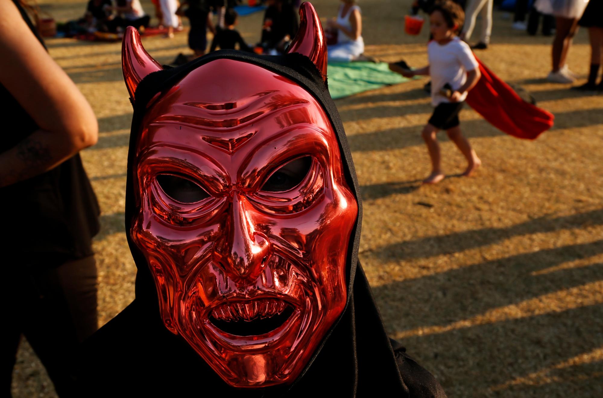 Un juerguista usa una máscara satánica durante las celebraciones para conmemorar Halloween en un parque en Johannesburgo, Sudáfrica, el jueves 31 de octubre de 2019.