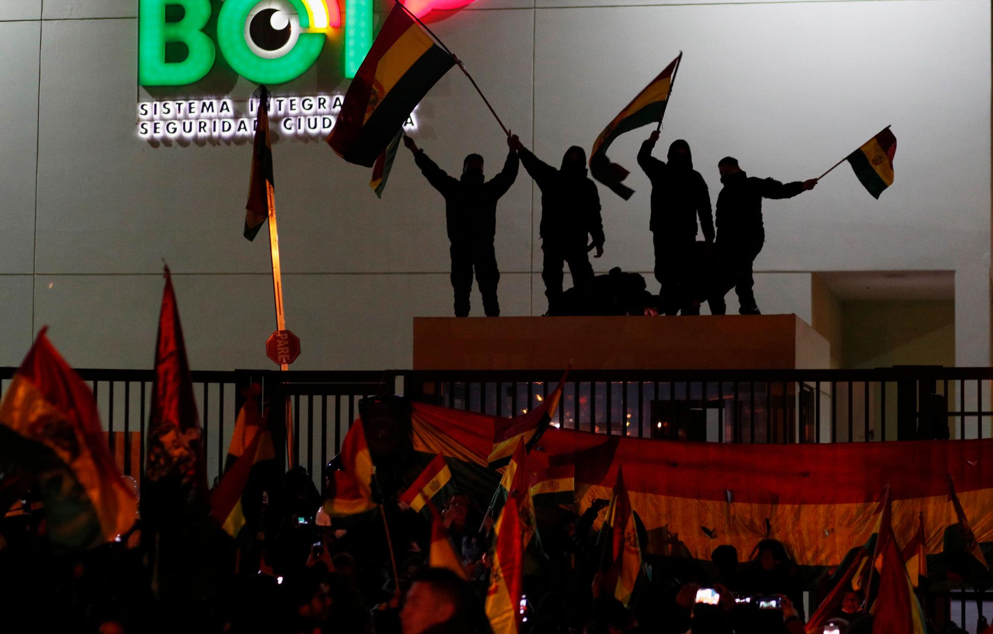 Los oficiales de policía parados en la azotea de una caseta de seguridad en una estación de policía ondean banderas bolivianas frente a los manifestantes en La Paz, Bolivia, el sábado 9 de noviembre de 2019. La creciente disensión en las filas policiales planteó una nueva amenaza para el presidente Evo Morales, quien reclamó la victoria después de la votación del 20 de octubre, pero desde entonces ha enfrentado protestas en las que tres personas han muerto y cientos han resultado heridas. 