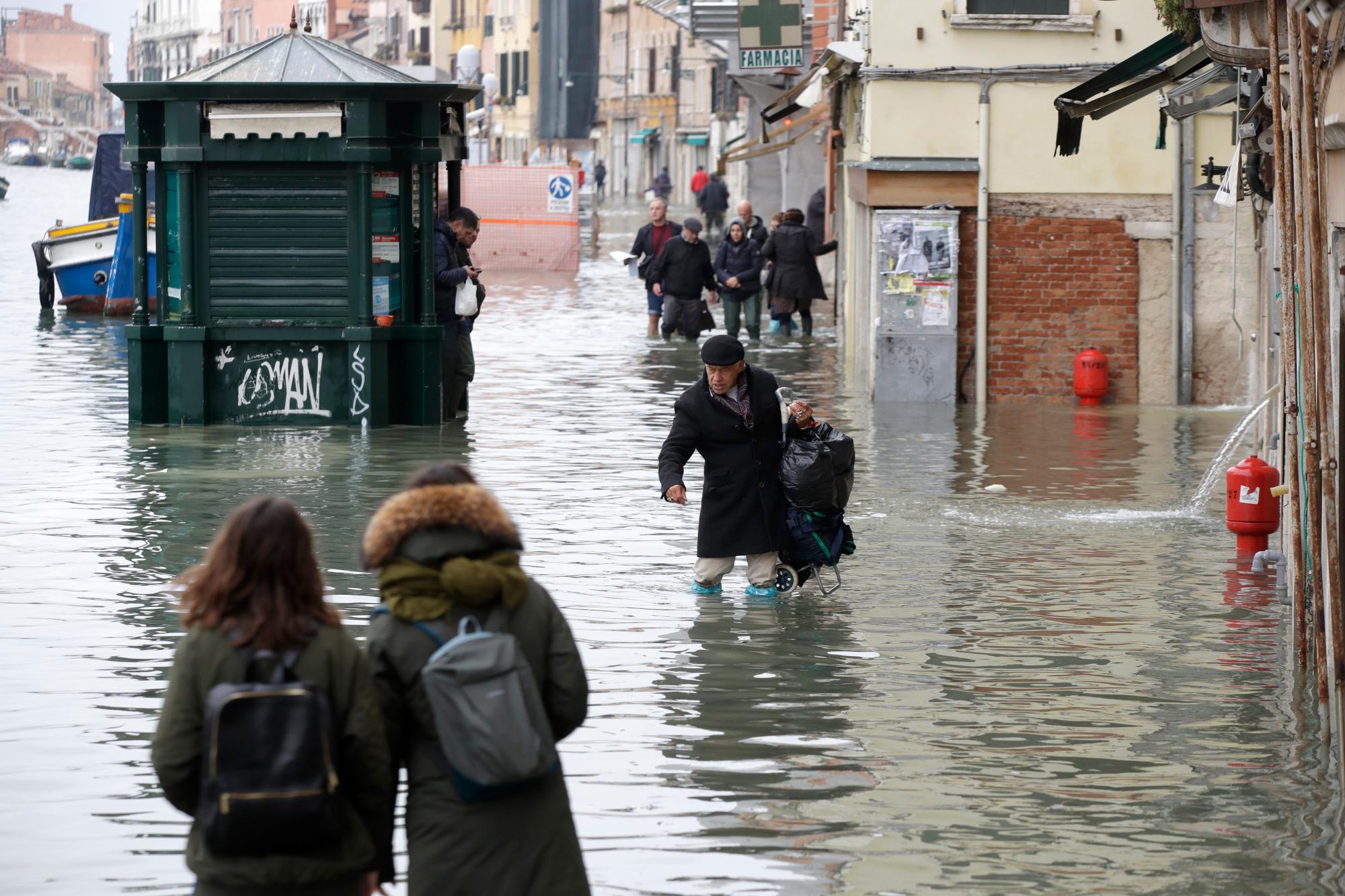La gente vadea el agua durante una marea alta, en Venecia, el miércoles 13 de noviembre de 2019. La marca de la marea alta golpeó 187 centímetros (74 pulgadas) el martes 12 de noviembre de 2019, lo que significa que más del 85% de la ciudad estaba inundado El nivel más alto jamás registrado fue de 194 centímetros (76 pulgadas) durante las inundaciones infames en 1966.