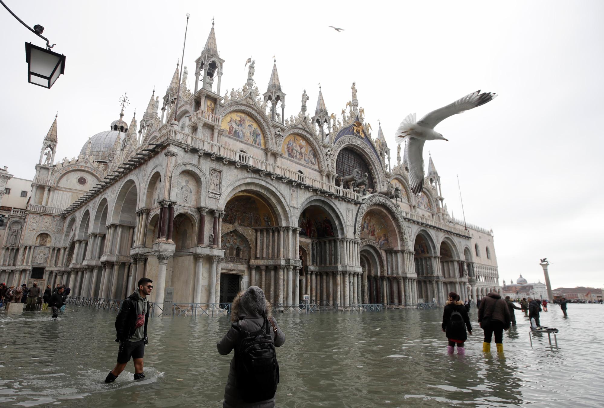 La gente vadeó en aguas altas, en Venecia, el miércoles 13 de noviembre de 2019. La marca de agua alta golpeó 187 centímetros (74 pulgadas) el martes 12 de noviembre de 2019, lo que significa que más del 85% de la ciudad se inundó. El nivel más alto jamás registrado fue de 194 centímetros (76 pulgadas) durante las inundaciones infames en 1966.
