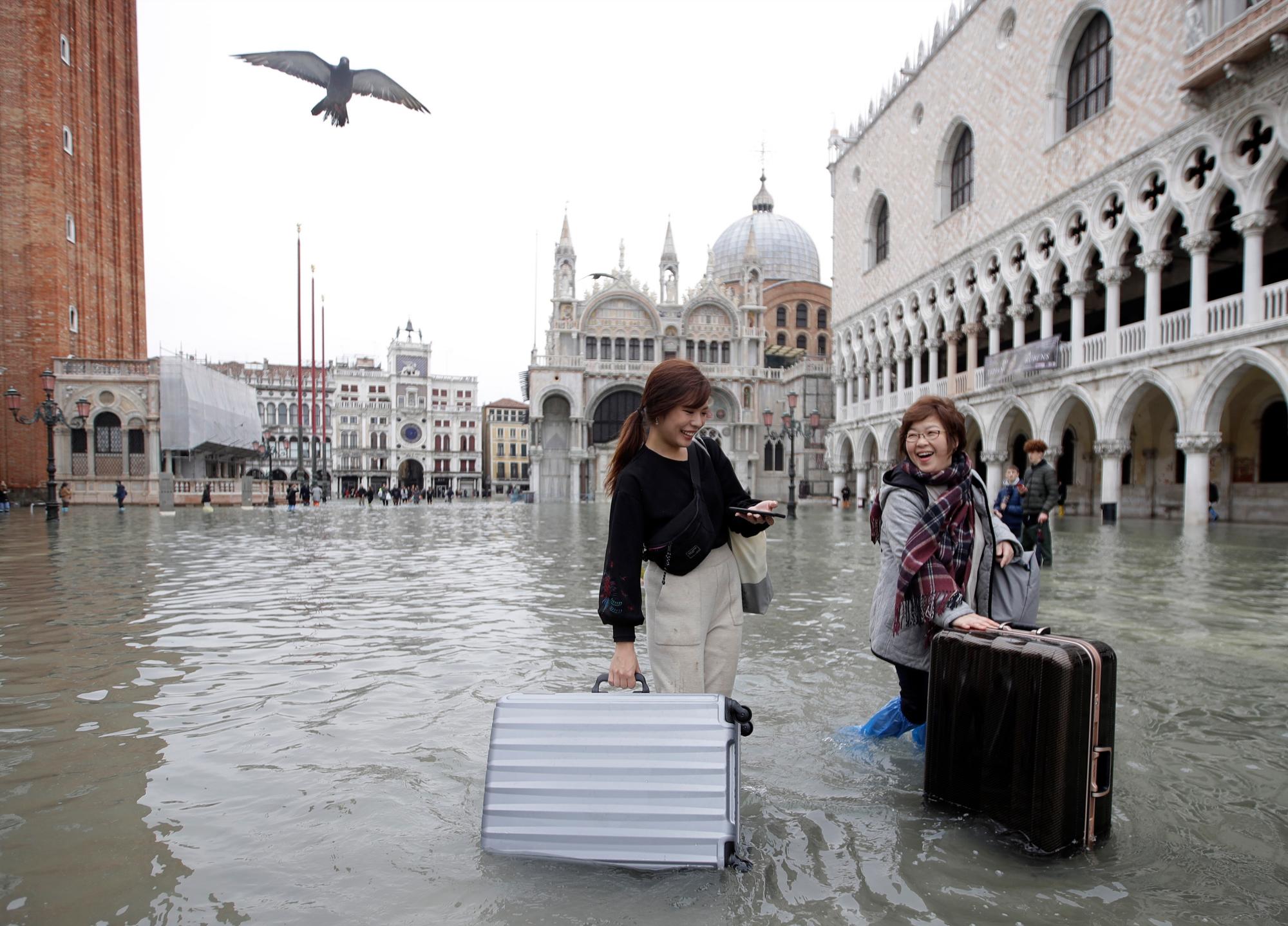 Los turistas empujan su equipaje en la inundada Plaza de San Marcos, en Venecia, el miércoles 13 de noviembre de 2019. La marca de la marea alta golpeó 187 centímetros (74 pulgadas) la noche del martes 12 de noviembre de 2019, lo que significa más del 85% de La ciudad se inundó. El nivel más alto jamás registrado fue de 194 centímetros (76 pulgadas) durante las inundaciones infames en 1966. 