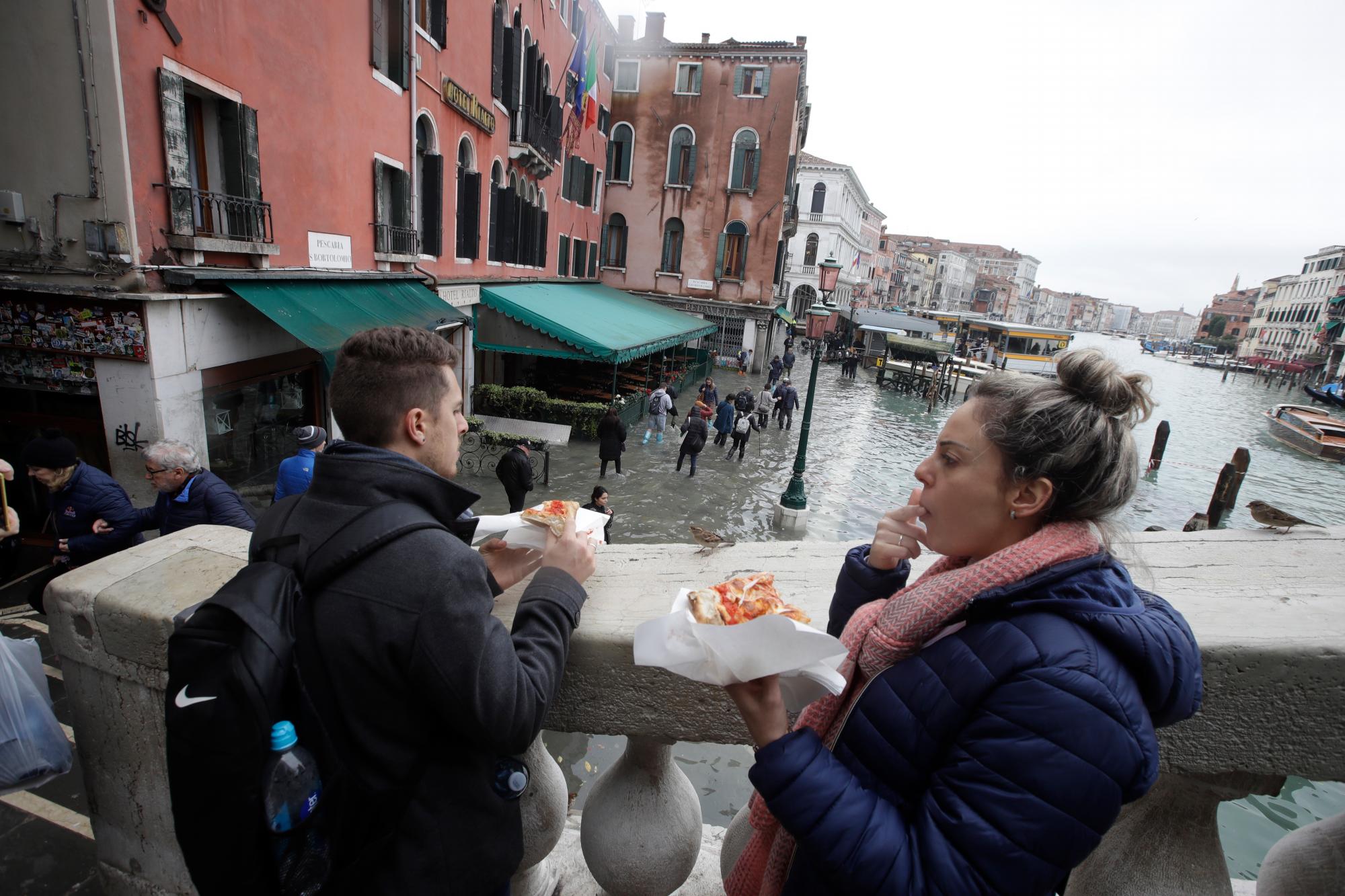 Una mujer mira el Puente de Rialto durante el apogeo, en Venecia, el miércoles 13 de noviembre de 2019. La marca del apogeo golpeó 187 centímetros (74 pulgadas) el martes 12 de noviembre de 2019, lo que significa más del 85% del La ciudad fue inundada. El nivel más alto jamás registrado fue de 194 centímetros (76 pulgadas) durante las inundaciones infames en 1966. 