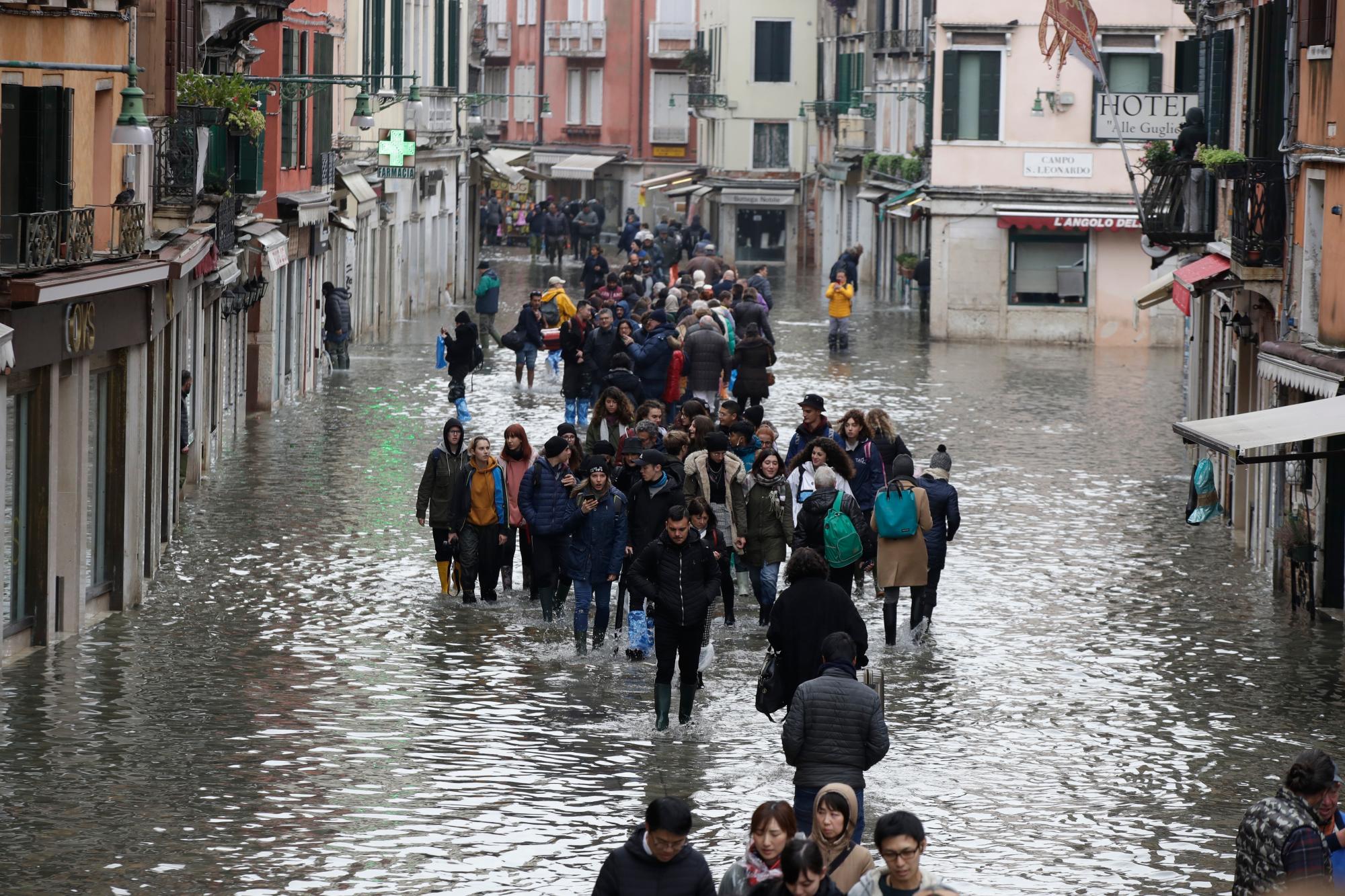La gente vadea por el agua en Venecia el miércoles 13 de noviembre de 2019. La marca de marea alta golpeó 187 centímetros (74 pulgadas) la noche del martes 12 de noviembre de 2019, lo que significa que más del 85% de la ciudad se inundó. El nivel más alto jamás registrado fue de 194 centímetros (76 pulgadas) durante las inundaciones infames en 1966.