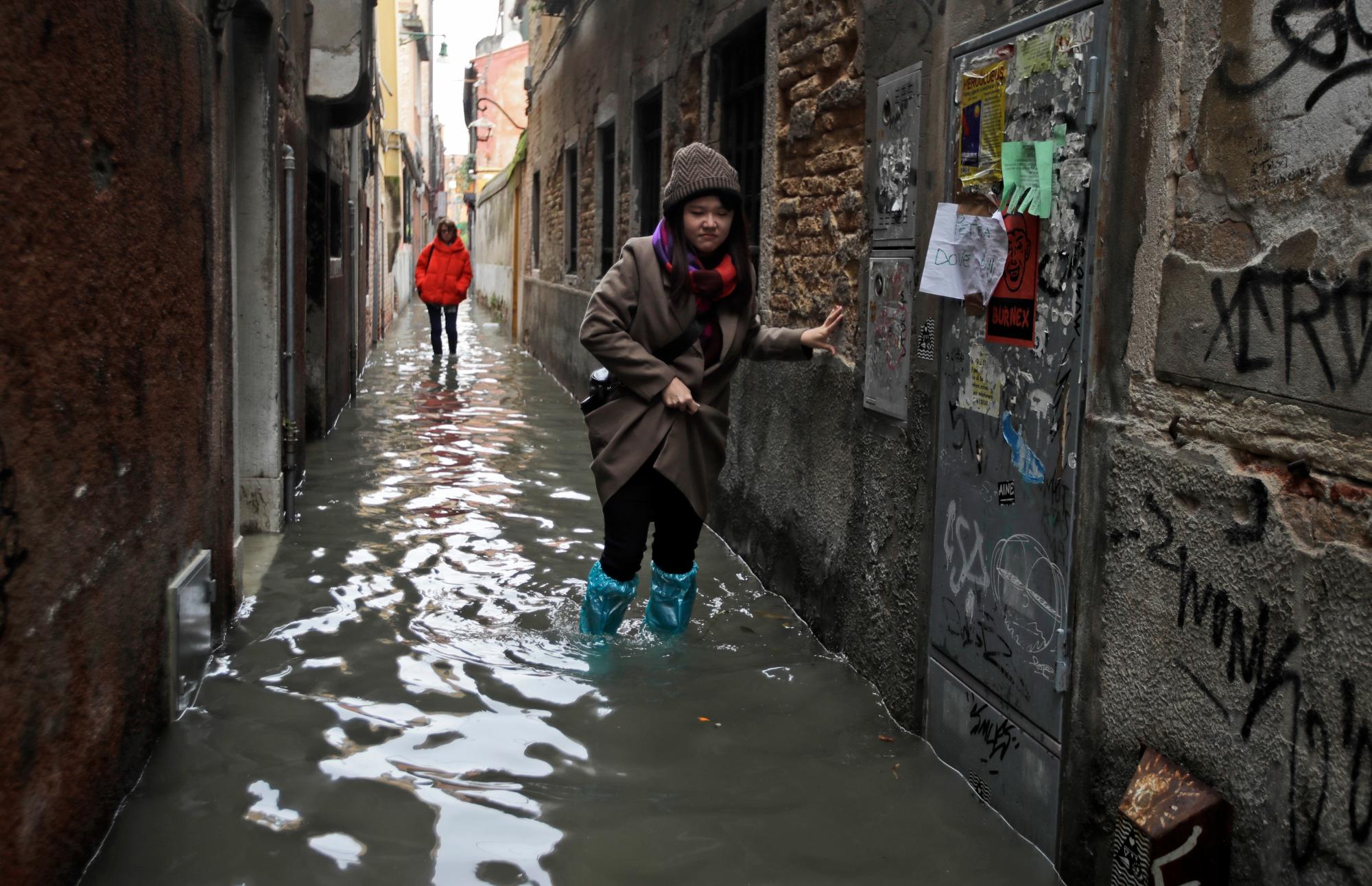Las mujeres caminan por el agua en Venecia, el miércoles 13 de noviembre de 2019. La marca de marea alta golpeó 187 centímetros (74 pulgadas) la noche del martes 12 de noviembre de 2019, lo que significa que más del 85% de la ciudad se inundó. El nivel más alto jamás registrado fue de 194 centímetros (76 pulgadas) durante las inundaciones infames en 1966.