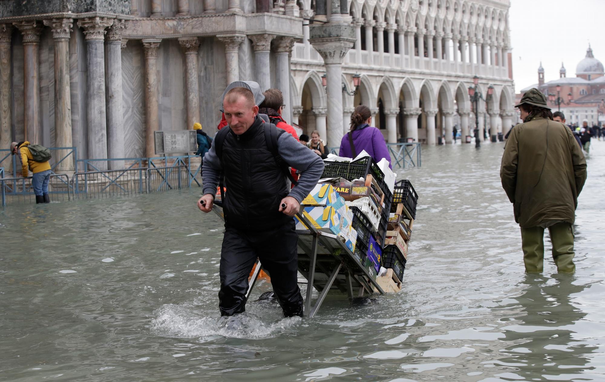 Un verdulero tira su carro a través del agua en Venecia, el miércoles 13 de noviembre de 2019. La marca de agua alta golpeó 187 centímetros (74 pulgadas) el martes 12 de noviembre de 2019, lo que significa que más del 85% de la ciudad se inundó . El nivel más alto jamás registrado fue de 194 centímetros (76 pulgadas) durante las inundaciones infames en 1966.