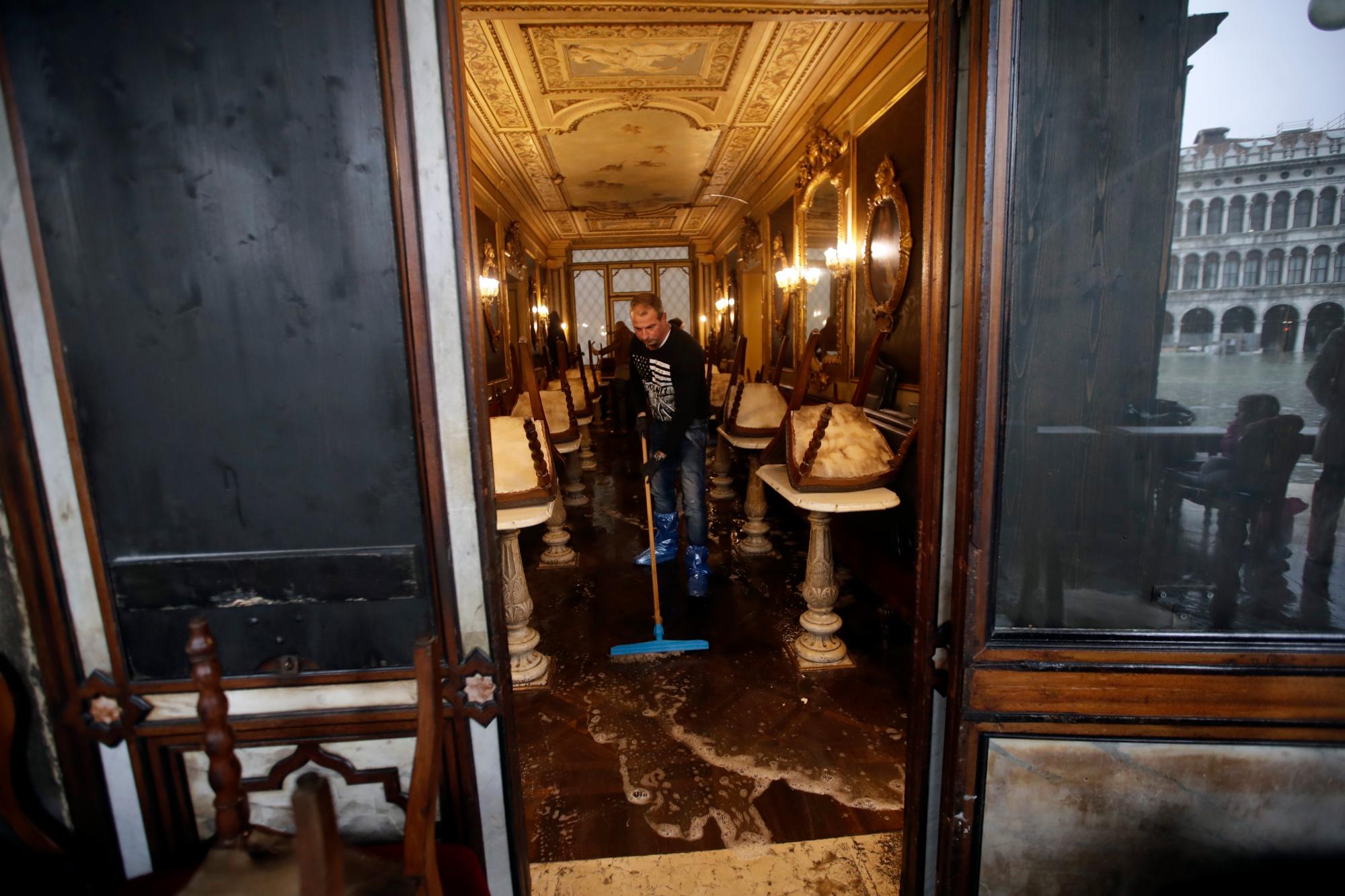 Un hombre limpia el agua de un café, en Venecia, el miércoles 13 de noviembre de 2019. La marca de agua alta golpeó 187 centímetros (74 pulgadas) el martes 12 de noviembre de 2019, lo que significa que más del 85% de la ciudad estaba inundado El nivel más alto jamás registrado fue de 194 centímetros (76 pulgadas) durante las inundaciones infames en 1966.