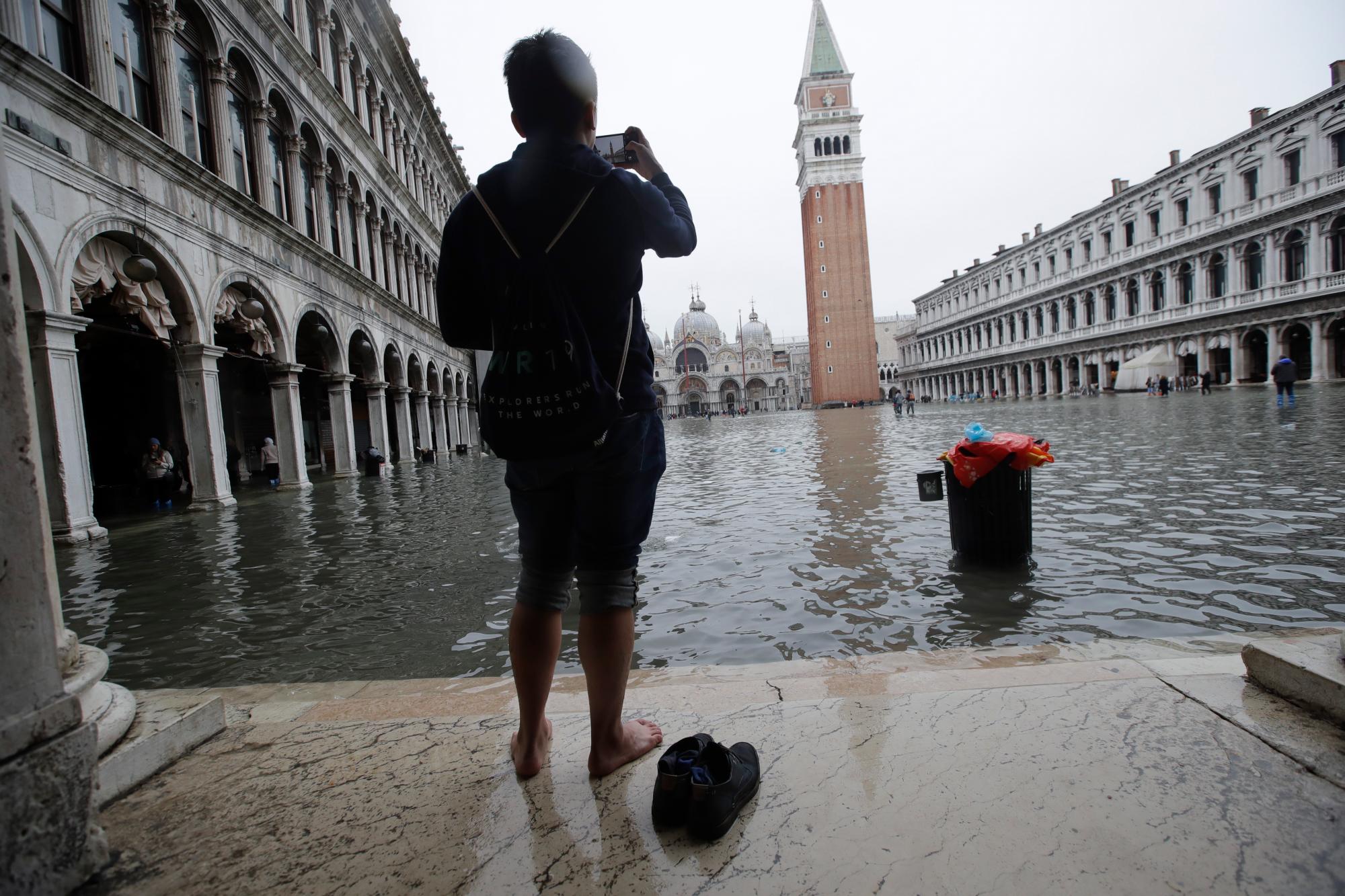 Un hombre toma fotos en una inundada Plaza de San Marcos, en Venecia, el miércoles 13 de noviembre de 2019. La marca de marea alta golpeó 187 centímetros (74 pulgadas) la noche del martes 12 de noviembre de 2019, lo que significa más del 85% de La ciudad se inundó. El nivel más alto jamás registrado fue de 194 centímetros (76 pulgadas) durante las inundaciones infames en 1966. 