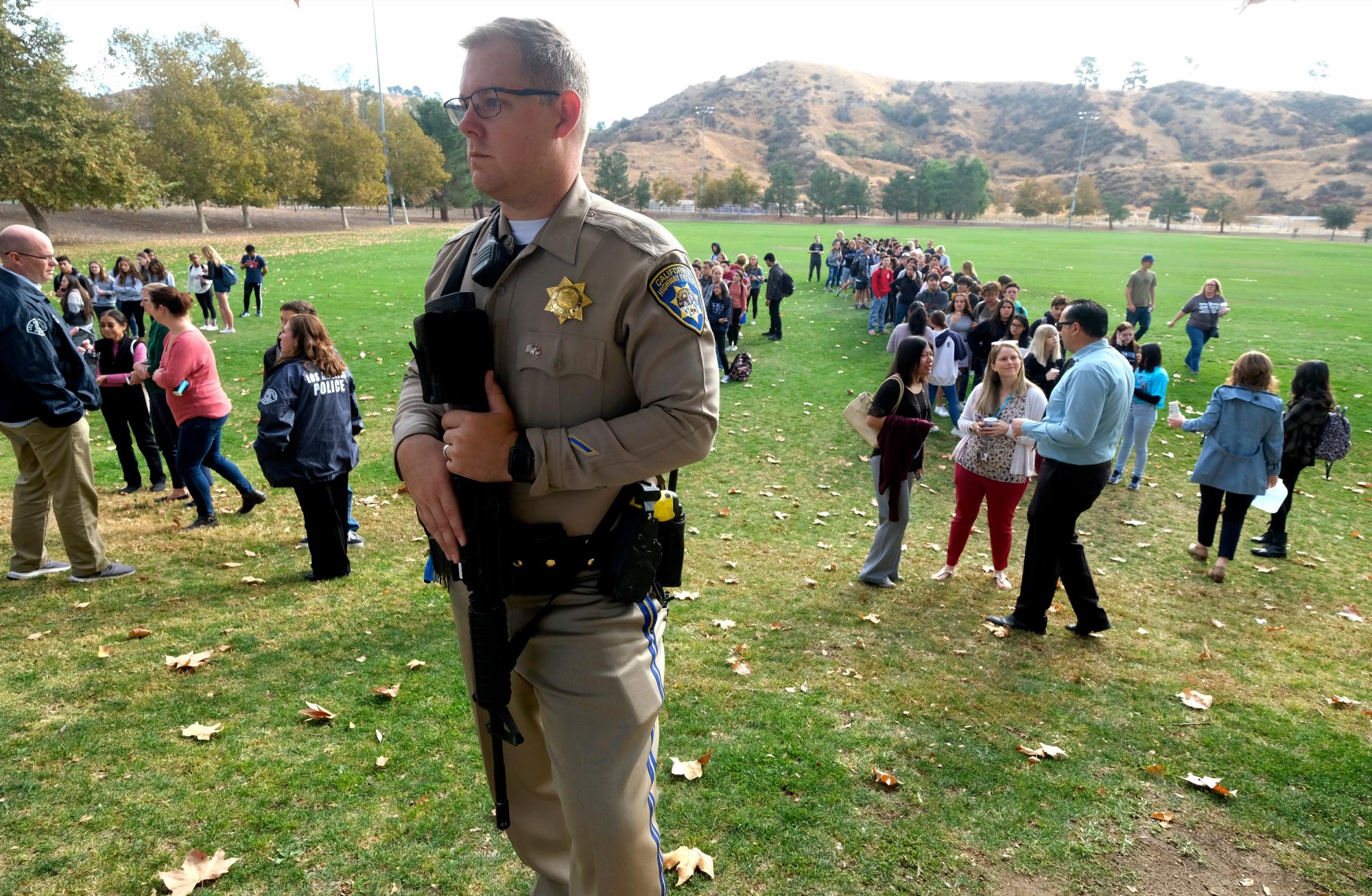 Un oficial de policía hace guardia mientras los estudiantes esperan reunirse con sus padres después de un tiroteo en la escuela secundaria Saugus que hirió a varias personas, el jueves 14 de noviembre de 2019, en Santa Clarita, California 