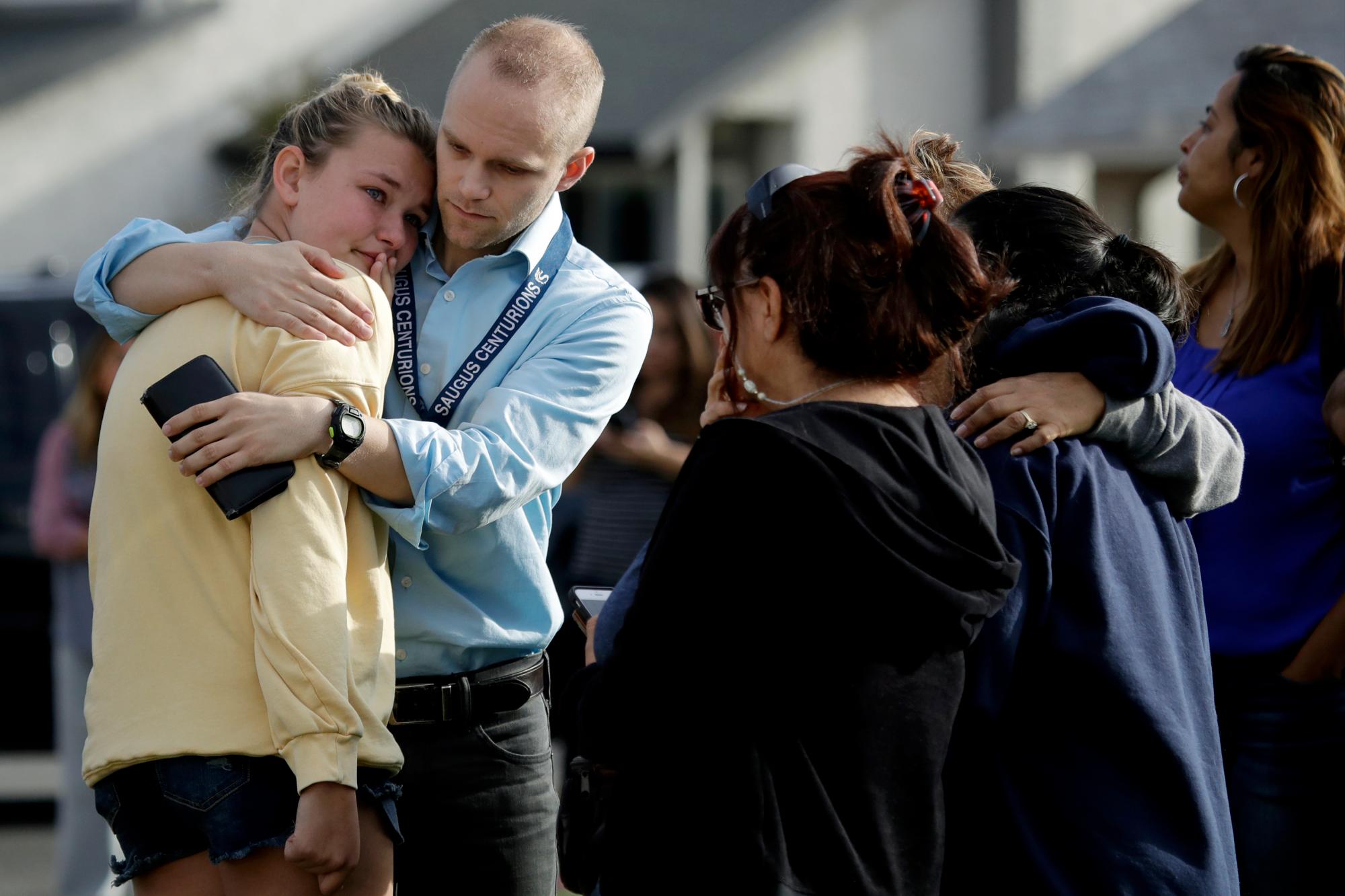 DJ. Hamburger, centro en azul, maestra en la escuela secundaria Saugus, consuela a un estudiante después de los informes de un tiroteo en la escuela el jueves 14 de noviembre de 2019, en Santa Clarita, California 