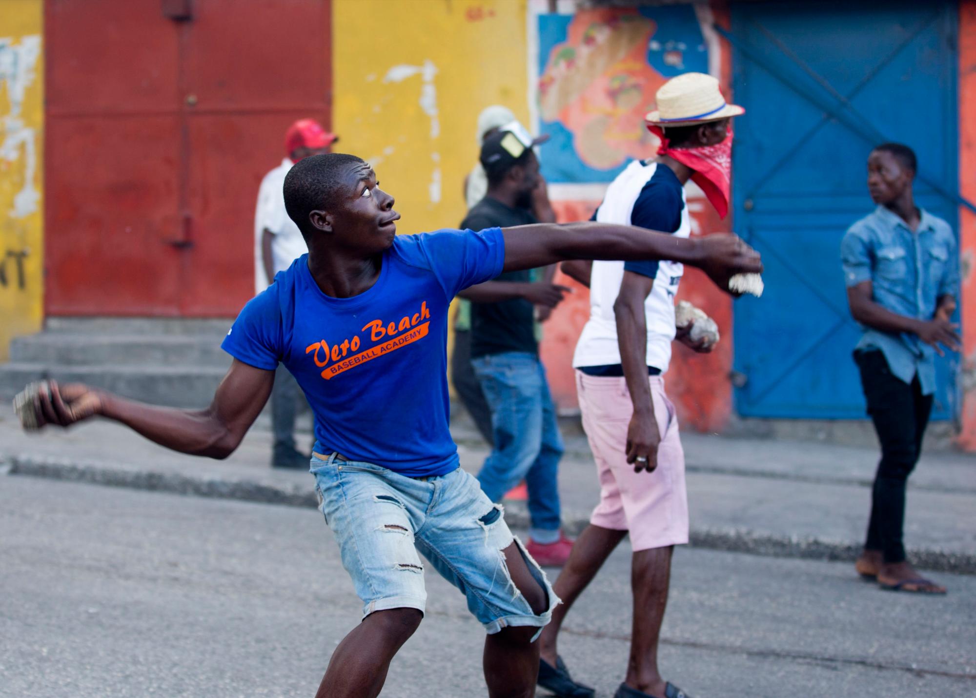 Los manifestantes arrojan piedras a los vecinos del vecindario durante una protesta para exigir la renuncia del presidente de Haití, Jovenel Moise, en el 216 aniversario de la Batalla de Vertieres en Puerto Príncipe, Haití, el lunes 18 de noviembre de 2019. Al menos cuatro personas fueron baleadas y herido durante una pequeña protesta en la capital de Haití después de un discurso del presidente asediado Moise. Un periodista local, un oficial de policía y dos manifestantes fueron trasladados rápidamente con heridas de bala aparentes.