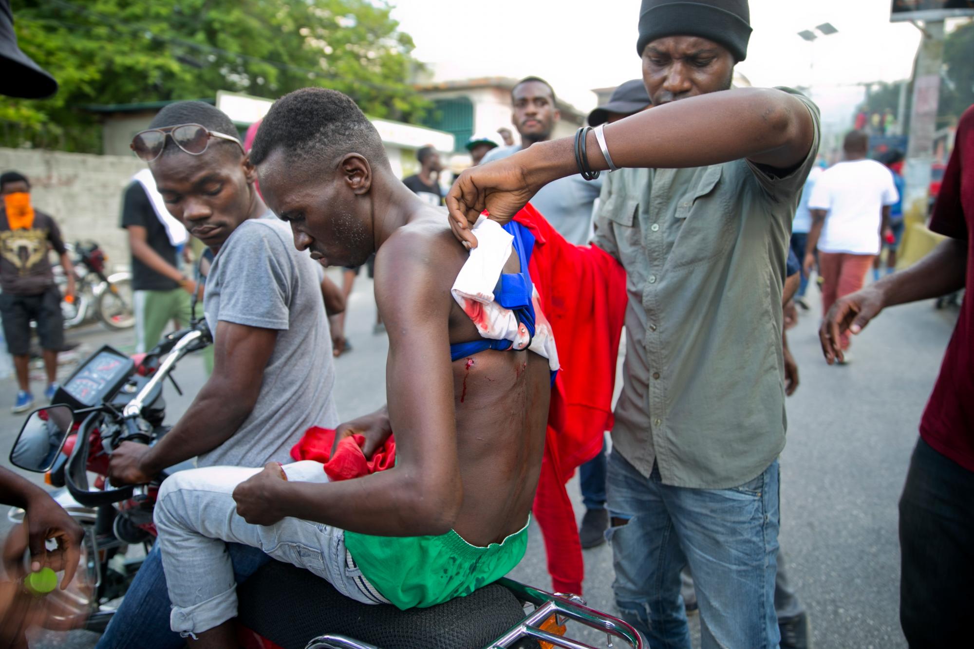 Un hombre herido es evacuado en una motocicleta durante los enfrentamientos para exigir la renuncia del presidente de Haití, Jovenel Moise, en el 216 aniversario de la Batalla de Vertieres en Puerto Príncipe, Haití, el lunes 18 de noviembre de 2019. Al menos cuatro personas fueron baleadas. y herido durante una pequeña protesta en la capital de Haití después de un discurso del presidente asediado Jovenel Moise. Un periodista local, un oficial de policía y dos manifestantes fueron trasladados rápidamente con heridas de bala aparentes. 