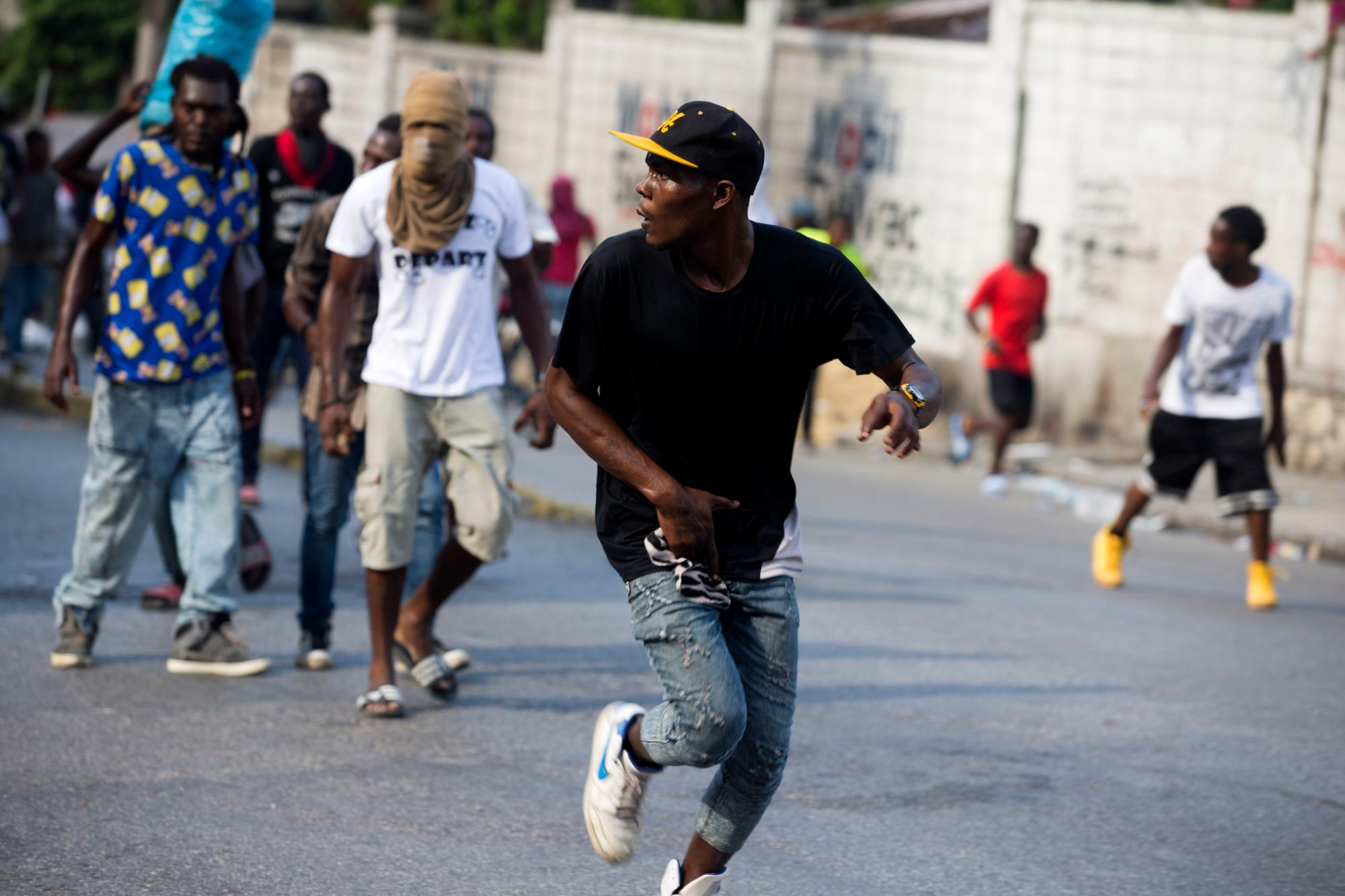 Un hombre busca un arma oculta durante una protesta para exigir la renuncia del presidente de Haití, Jovenel Moise, en el 216 aniversario de la Batalla de Vertieres en Puerto Príncipe, Haití, el lunes 18 de noviembre de 2019. Al menos cuatro personas fueron baleadas. y herido durante una pequeña protesta en la capital de Haití después de un discurso del presidente asediado Moise. Un periodista local, un oficial de policía y dos manifestantes fueron trasladados rápidamente con heridas de bala aparentes.