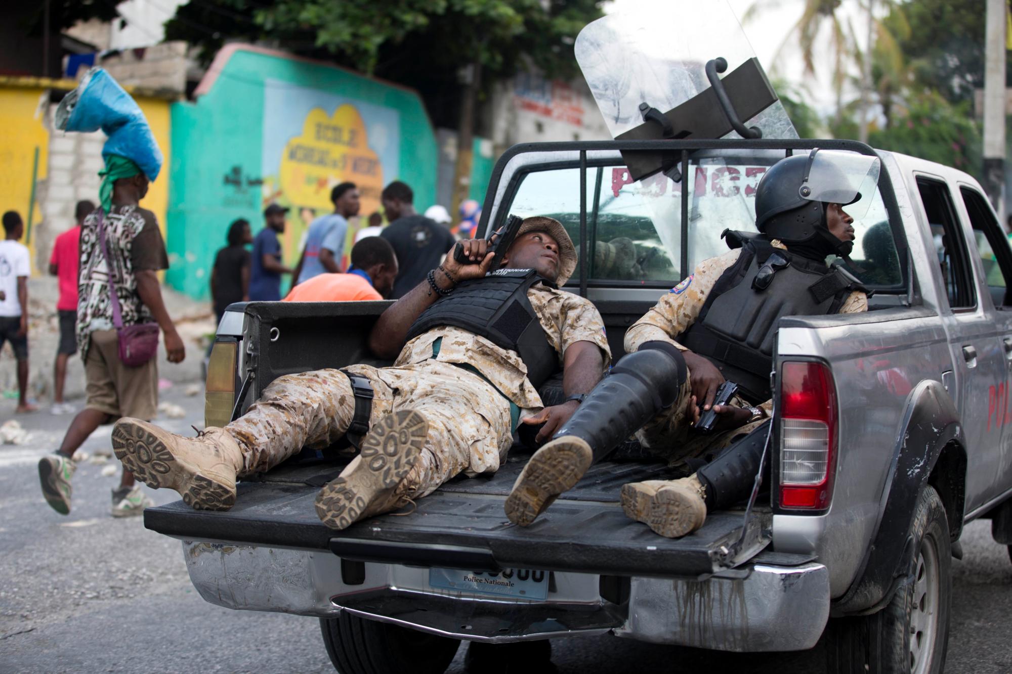 Oficiales de policía viajan en la parte trasera de una camioneta con sus armas desenfundadas durante una protesta para exigir la renuncia del presidente de Haití, Jovenel Moise, en el 216 aniversario de la Batalla de Vertieres en Puerto Príncipe, Haití, el lunes 18 de noviembre , 2019. Al menos cuatro personas fueron baleadas y heridas durante una pequeña protesta en la capital de Haití después de un discurso del presidente Moise. Un periodista local, un oficial de policía y dos manifestantes fueron trasladados rápidamente con heridas de bala aparentes.