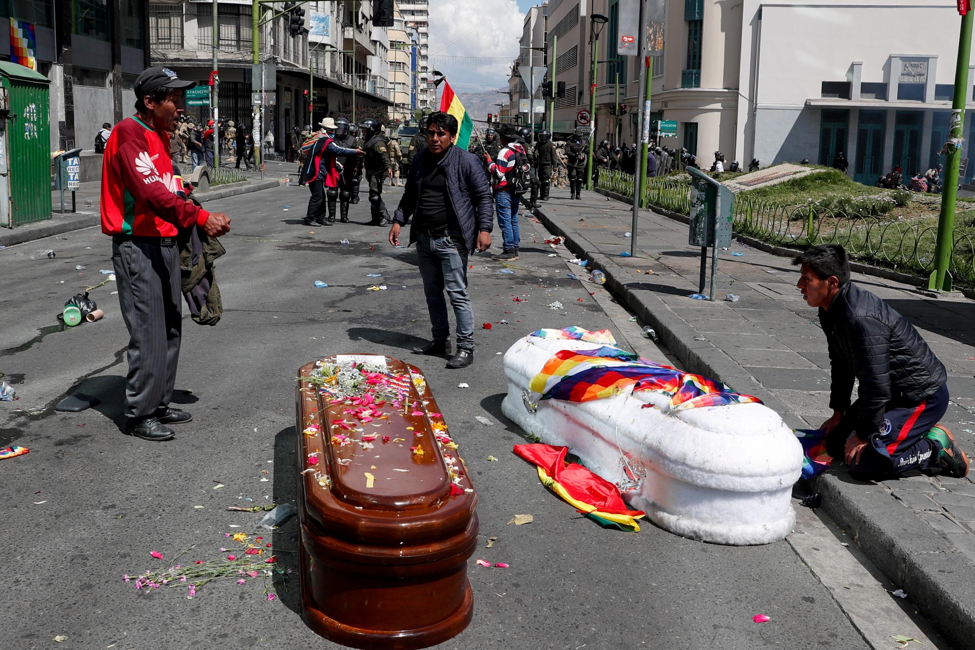 En esta fotografía del 21 de noviembre de 2019, dos ataúdes que contienen los restos de personas muertas durante enfrentamientos entre las fuerzas de seguridad y partidarios del expresidente Evo Morales yacen en la calle, luego de que la policía arrojó gases lacrimógenos a una enorme procesión fúnebre para dispersar a manifestantes antigubernamentales que acompañaban los féretros hacia La Paz, Bolivia. El país ha sido presa de la agitación desde que Morales renunció el 10 de noviembre tras semanas de protestas en su contra por unas controvertidas elecciones que, según una auditoría de la OEA, se vieron opacadas por irregularidades.