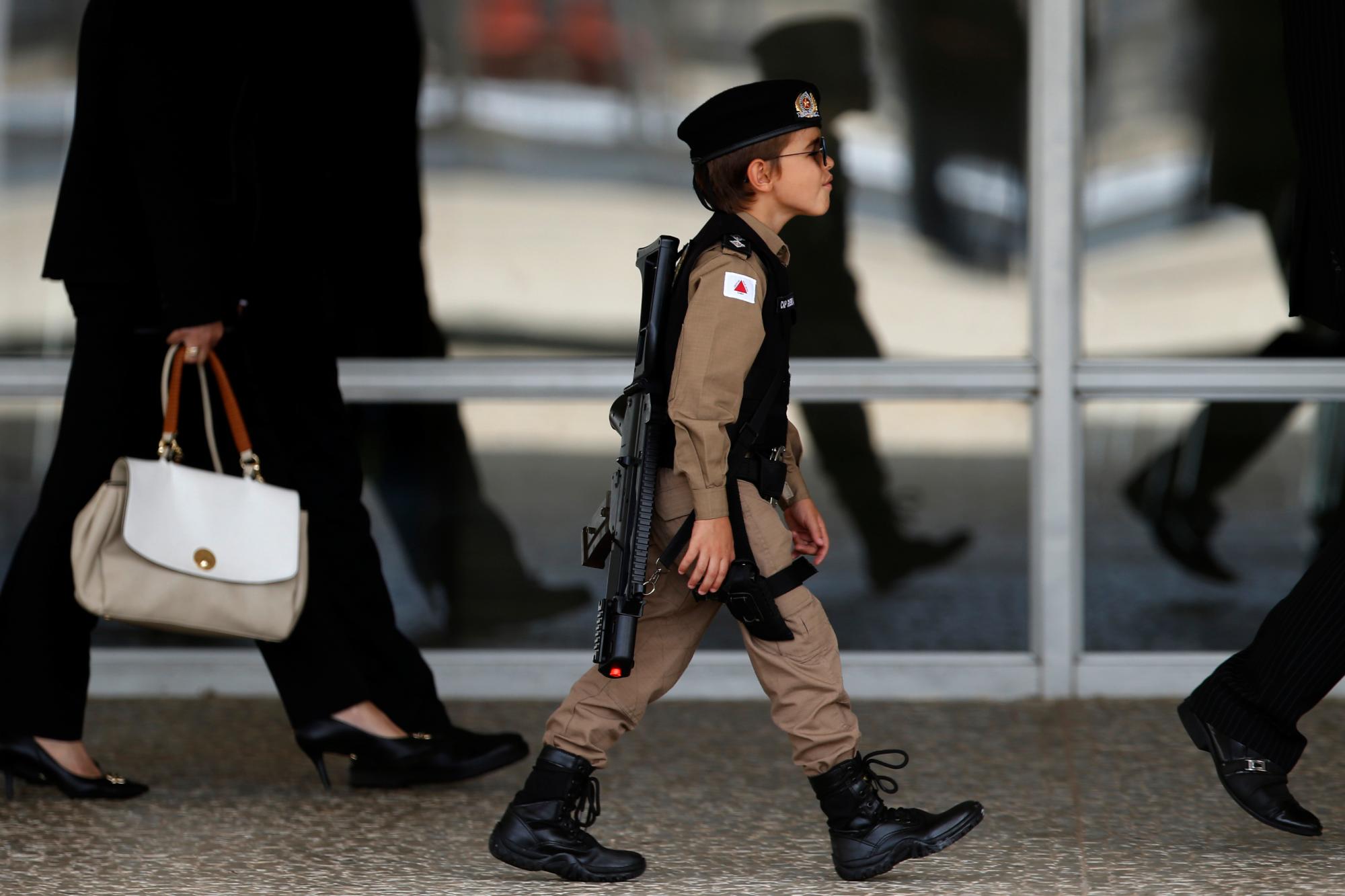 En esta fotografía del 28 de noviembre de 2019, un niño vestido con un uniforme similar al de la policía militar acude para ver el cambio de guardia en el Palacio Presidencial de Planalto, en Brasilia, Brasil. 
