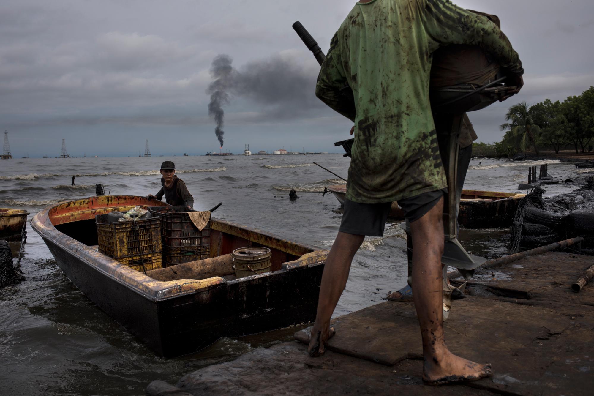 Los pescadores cubiertos de petróleo preparan su bote para pescar en el lago de Maracaibo, cerca de la terminal de envío de crudo La Salina en Cabimas, Venezuela, el 9 de julio de 2019.