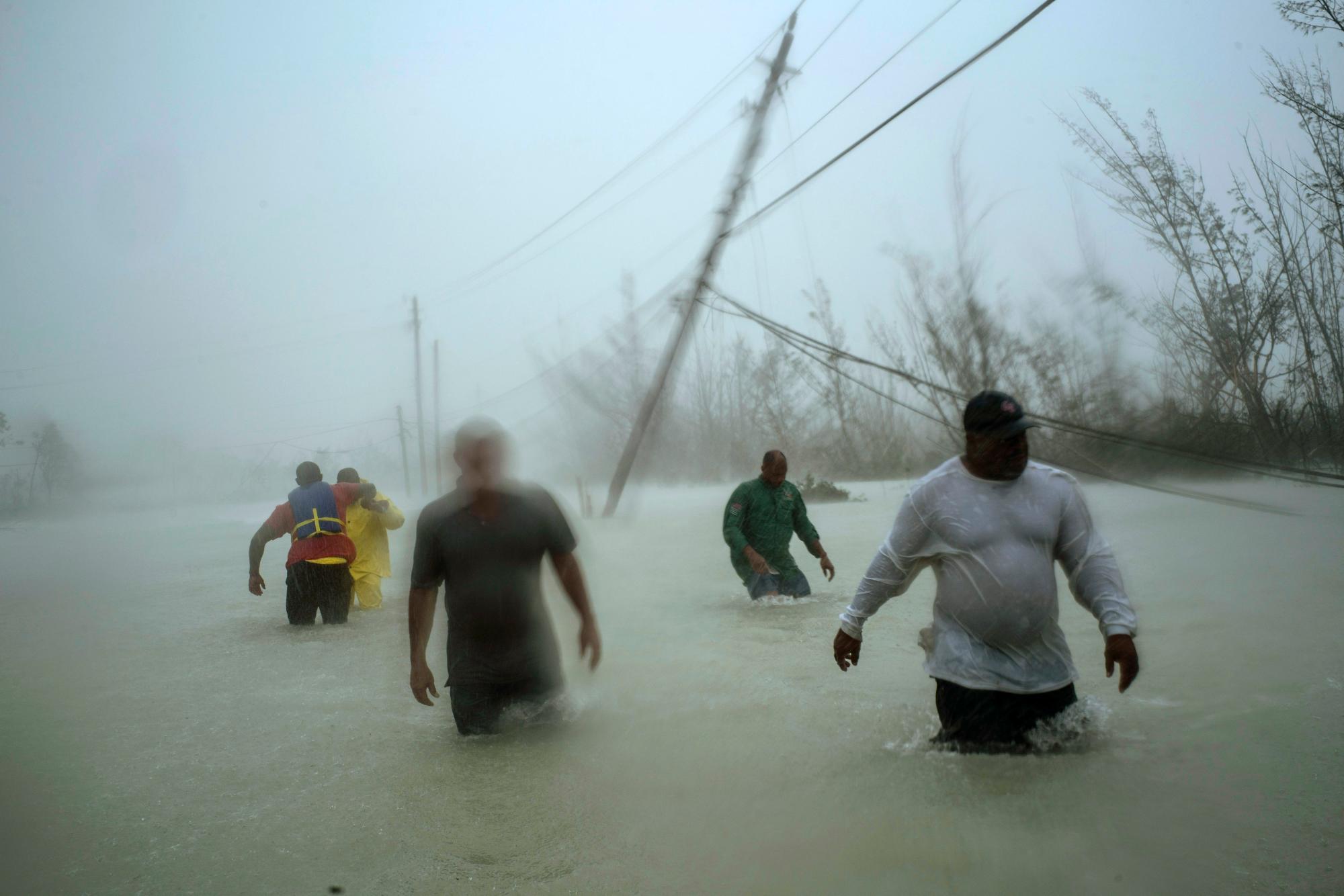 Los voluntarios caminan por un camino inundado contra el viento y la lluvia provocados por el huracán Dorian para rescatar a las familias cerca del puente Causarina en Freeport, Gran Bahama, Bahamas, el 3 de septiembre de 2019.