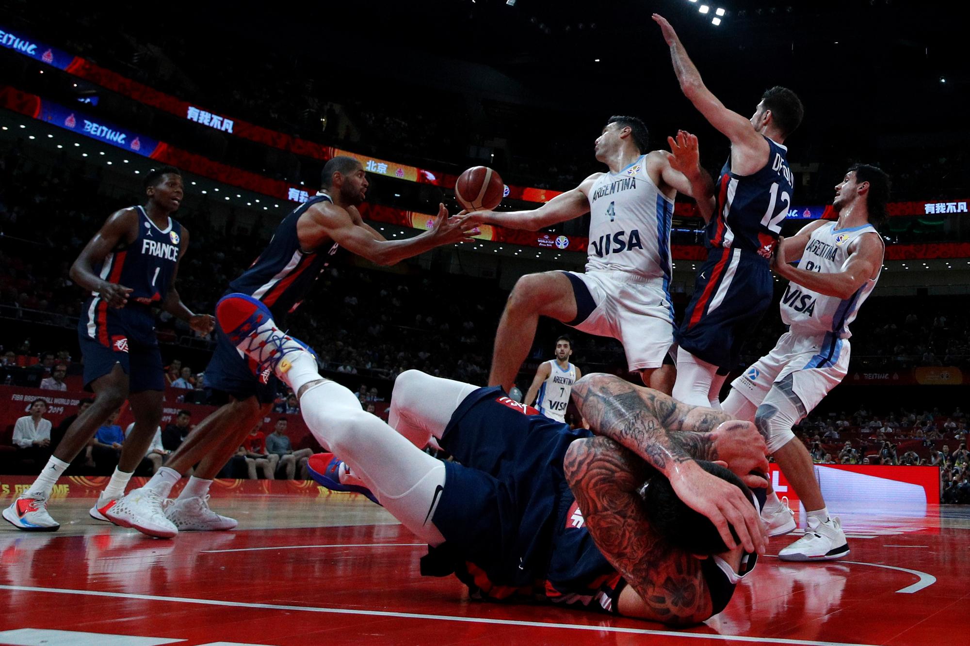 Vincent Poirier de Francia cae en la cancha mientras Luis Scola de Argentina lucha por el balón con Nicholas Batum, segundo desde la izquierda, durante su partido de semifinales para la Copa Mundial de Baloncesto FIBA en el Cadillac Arena en Beijing el 13 de septiembre de 2019. 