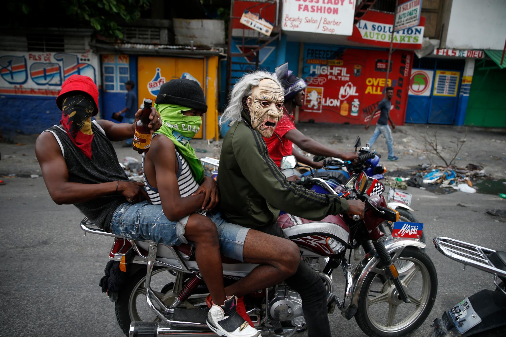 Manifestantes enmascarados manejan una motocicleta el 30 de septiembre de 2019 en Puerto Príncipe, Haití, donde los manifestantes prendieron fuego y pidieron la renuncia del presidente de Haití, Jovenel Moise.