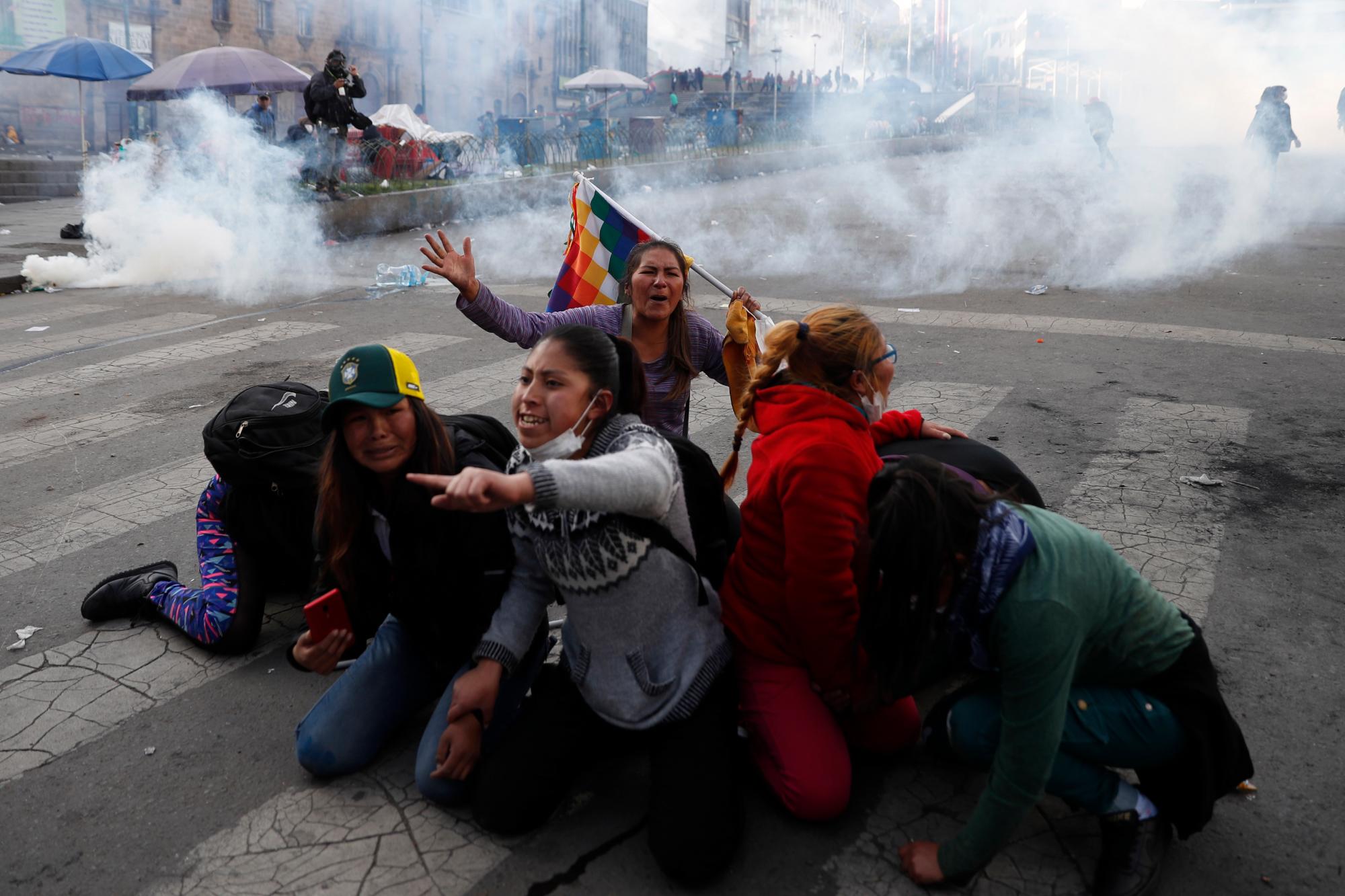 Los partidarios del ex presidente Evo Morales se protegen del gas lacrimógeno lanzado por la policía en La Paz, Bolivia, el 15 de noviembre de 2019. 