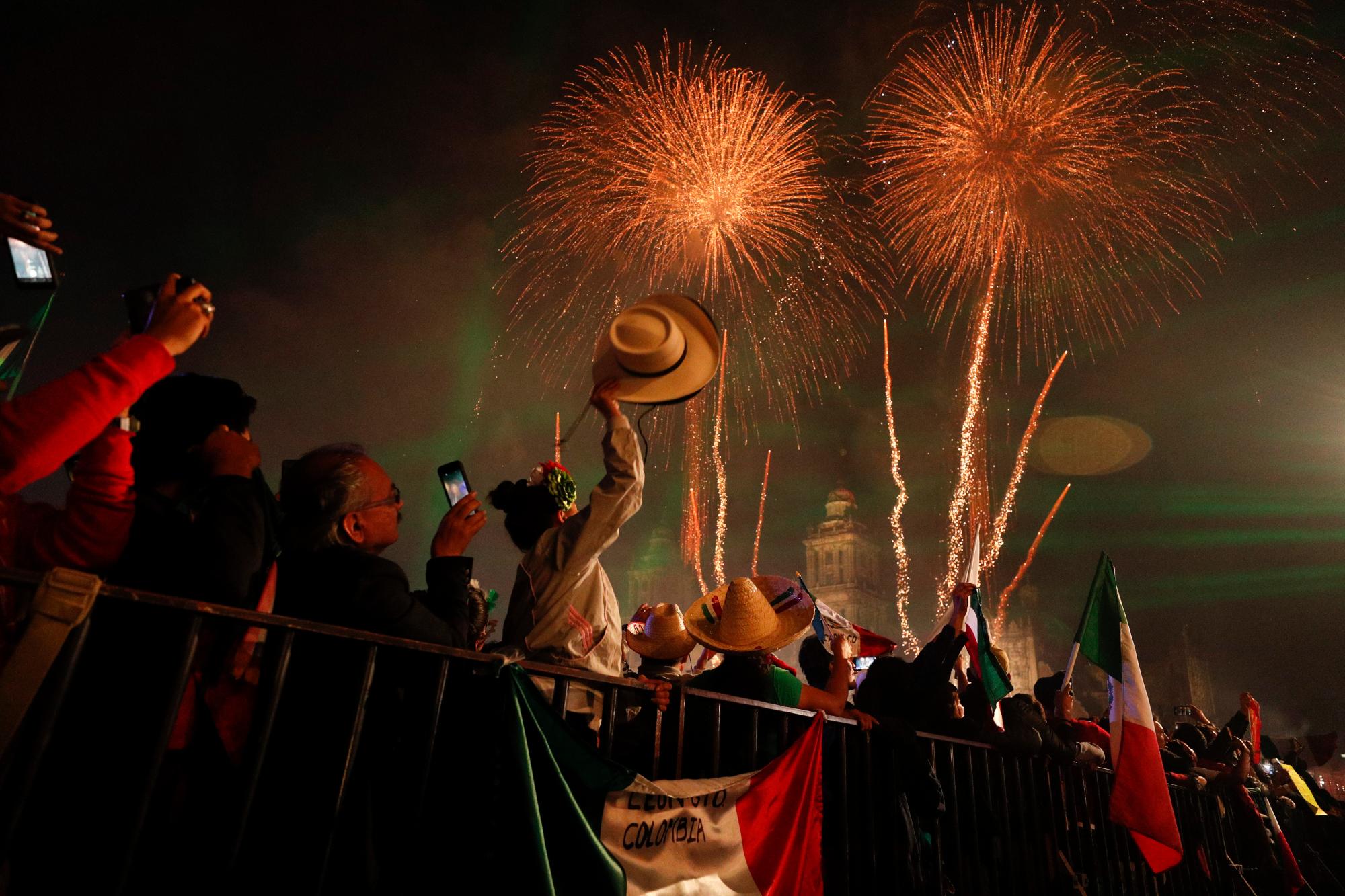 Los juerguistas celebran mientras los fuegos artificiales explotan sobre la Catedral Metropolitana de la Ciudad de México después de que el presidente Andrés Manuel López Obrador dio el grito de independencia anual desde el balcón del Palacio Nacional para comenzar las celebraciones del Día de la Independencia el 15 de septiembre de 2019. 