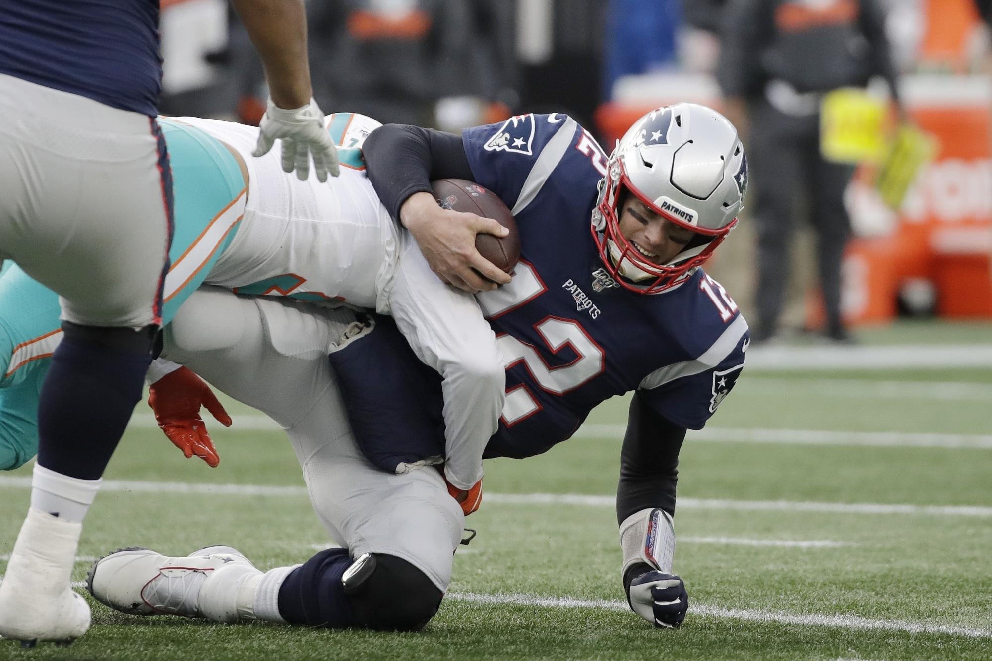 Tom Brady, quarterback de los Patriots de Nueva Inglaterra, es capturado por Trent Harris, de los Dolphins de Miami, el domingo 29 de diciembre de 2019 (AP Foto/Elise Amendola)