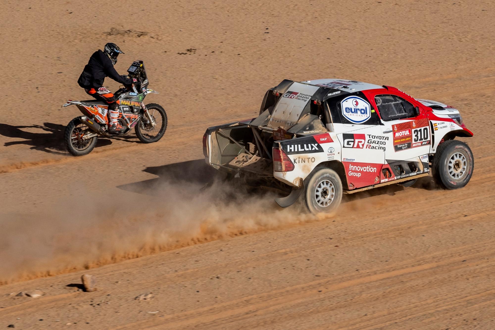 Driver Fernando Alonso, of Spain, and co-driver Marc Coma, of Spain, race their Toyota next to motorbiker Charlie Herbst of Franceduring stage four of the Dakar Rally between Neom and Al Ula, in Saudi Arabia, Wednesday, Jan. 8, 2020. (AP Photo/Bernat Armangue)
